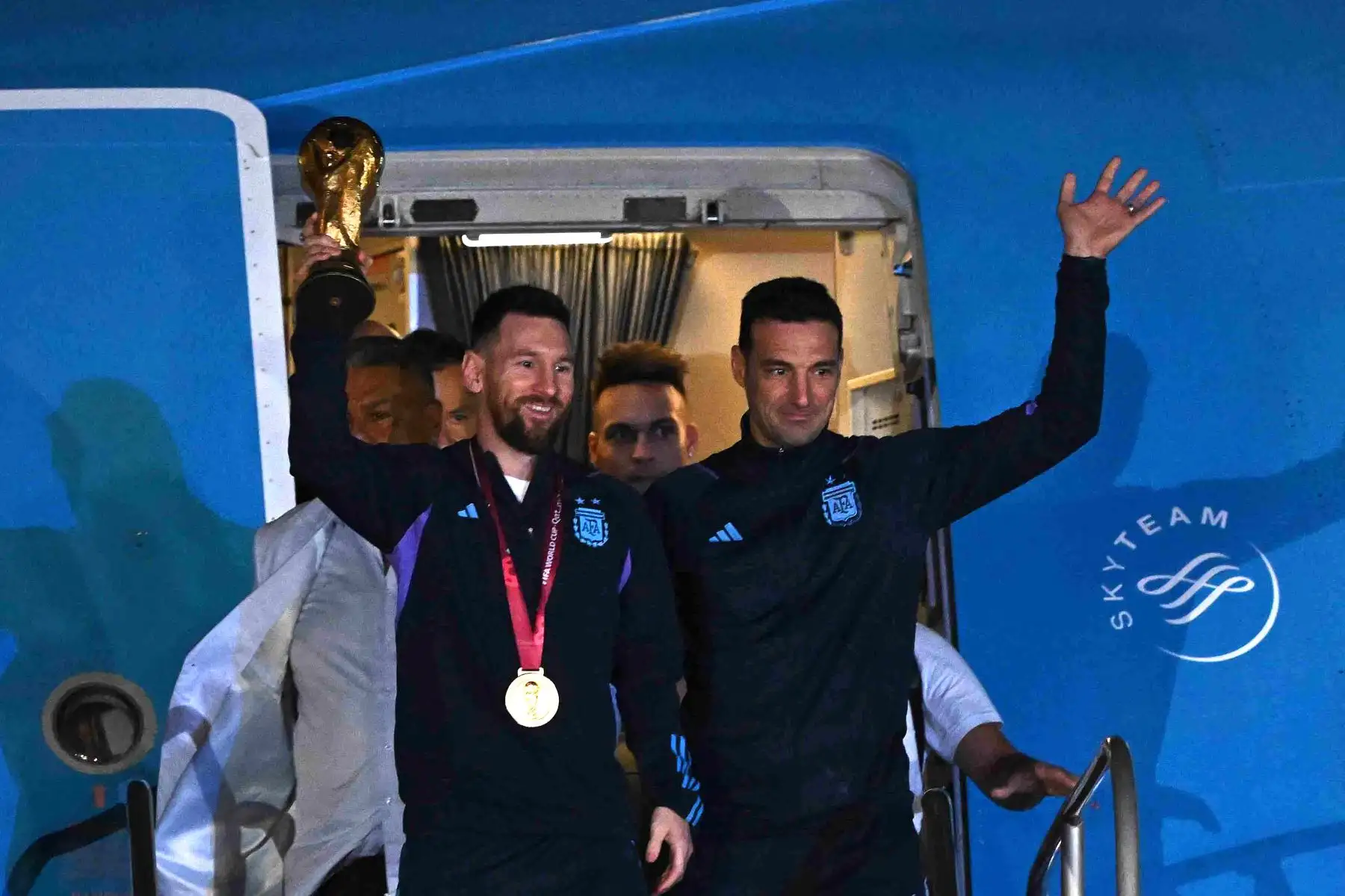 El capitán y delantero argentino Lionel Messi sostiene el Trofeo de la Copa Mundial de la FIFA junto con el entrenador argentino Lionel Scaloni cuando bajan de un avión al llegar al Aeropuerto Internacional de Ezeiza después de ganar el torneo de la Copa Mundial Qatar 2022 en Ezeiza, provincia de Buenos Aires, Argentina en diciembre 20 de febrero de 2022. Foto: AFP