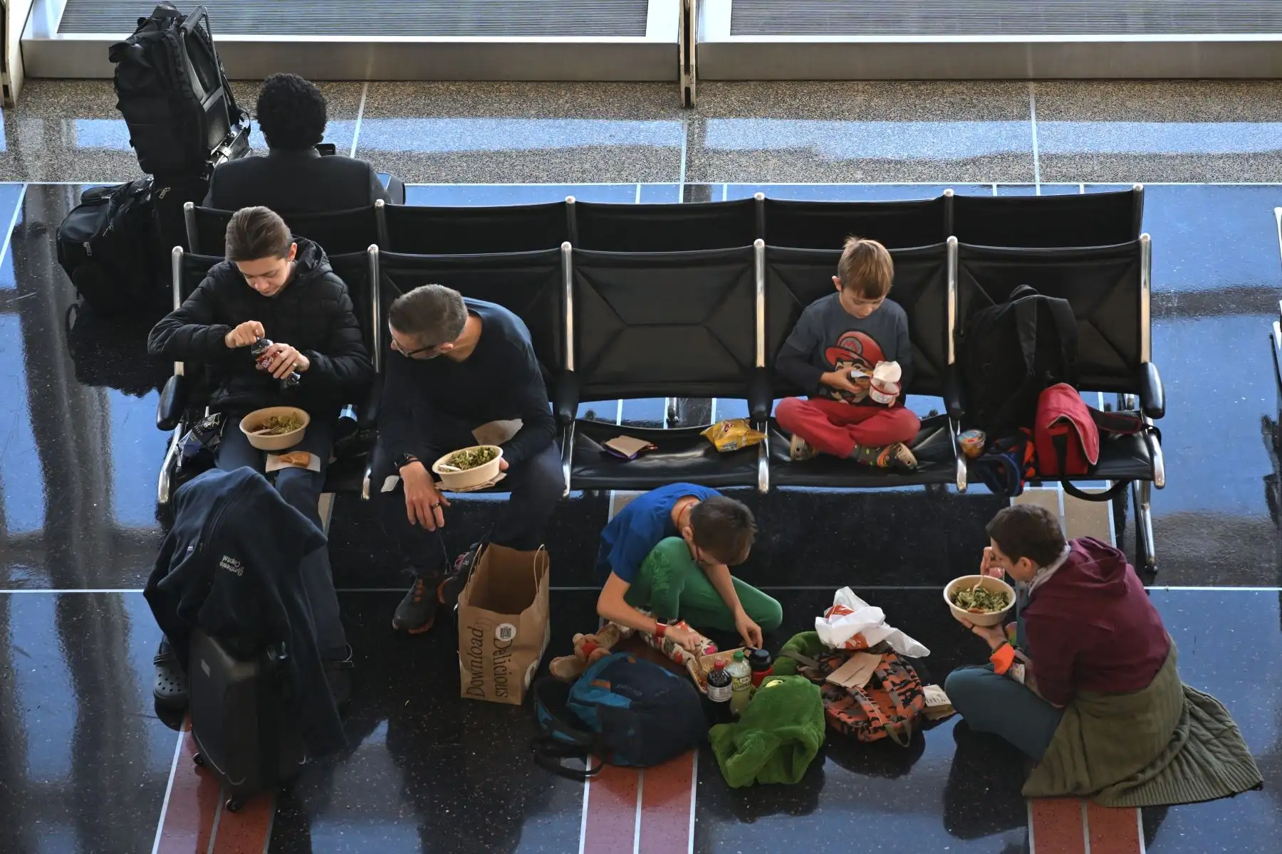 Una familia disfruta de una comida mientras esperan un vuelo en el Aeropuerto Nacional Reagan durante la tormenta de invierno antes de las vacaciones de Navidad, en Arlington, Virginia, el 23 de diciembre de 2022.
Foto: AFP