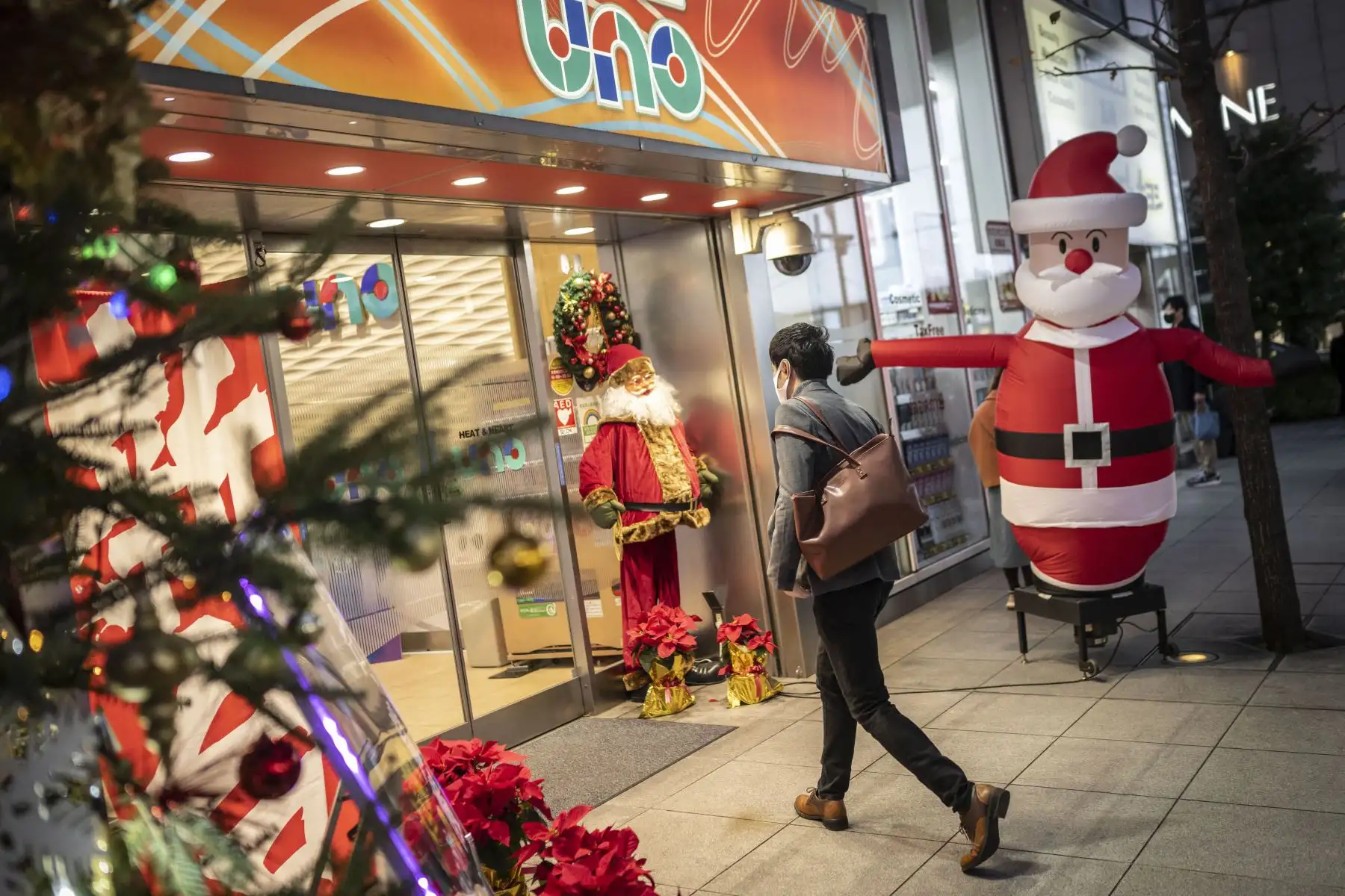 Un hombre entra a un salón de pachinko con adornos navideños en Tokio el 24 de diciembre de 2022. Foto:AFP
