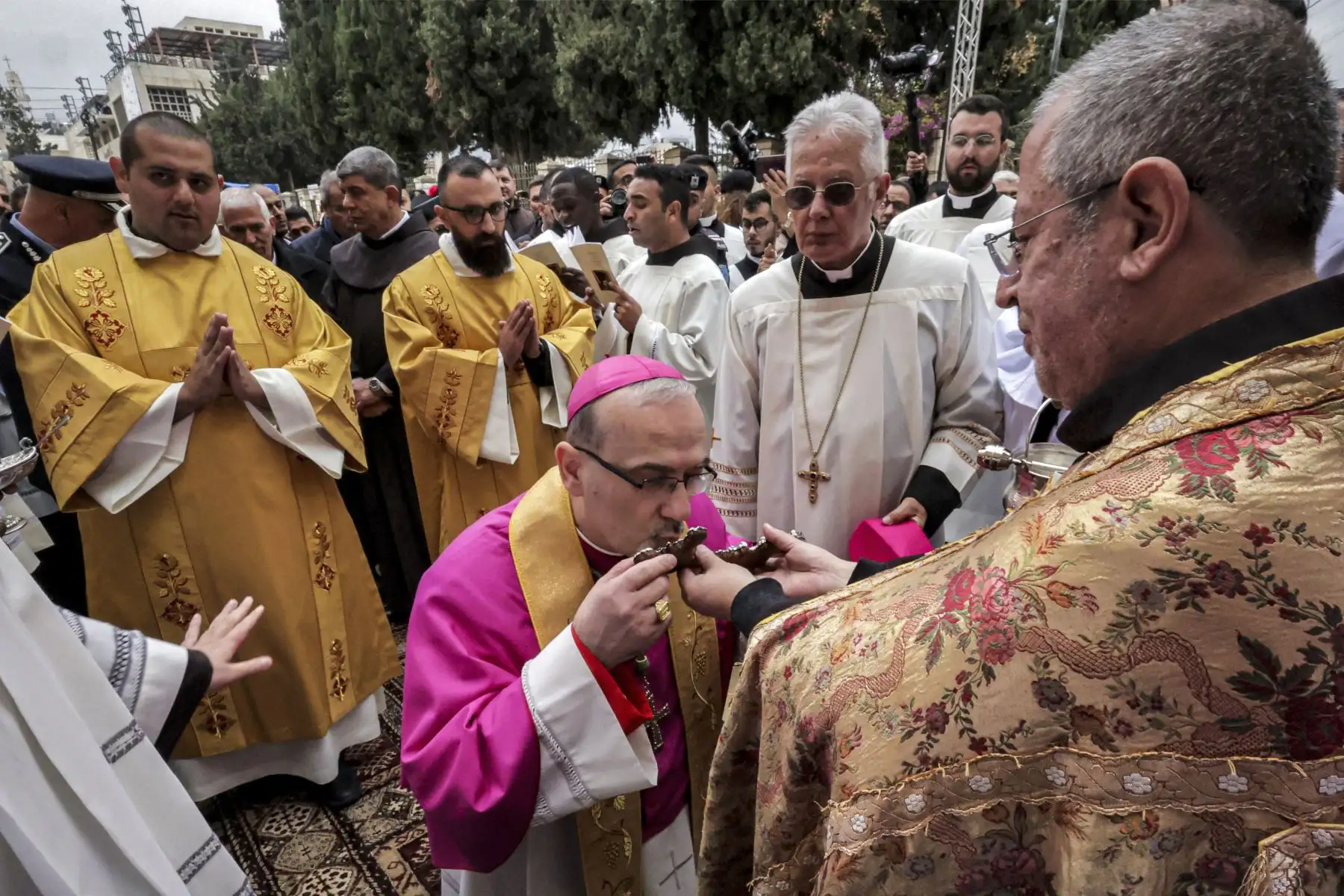El patriarca latino de Jerusalén Pierbattista Pizzaballa se inclina para besar el crucifijo de un clérigo cuando llega para el servicio de Navidad fuera de la Iglesia de la Natividad en la ciudad bíblica de Belén.Foto: AFP