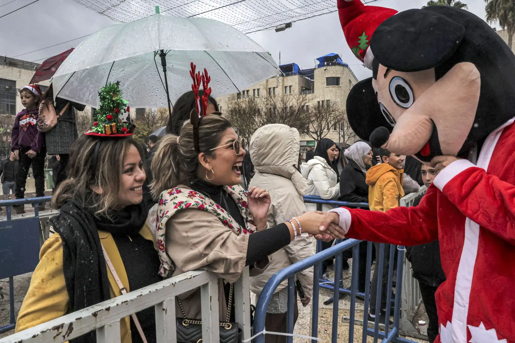Un juerguista es recibido por una persona vestida con el traje de la mascota de Mickey Mouse en la Plaza del Pesebre fuera de la Iglesia de la Natividad en la ciudad bíblica de Belén en Cisjordania. Foto: AFP