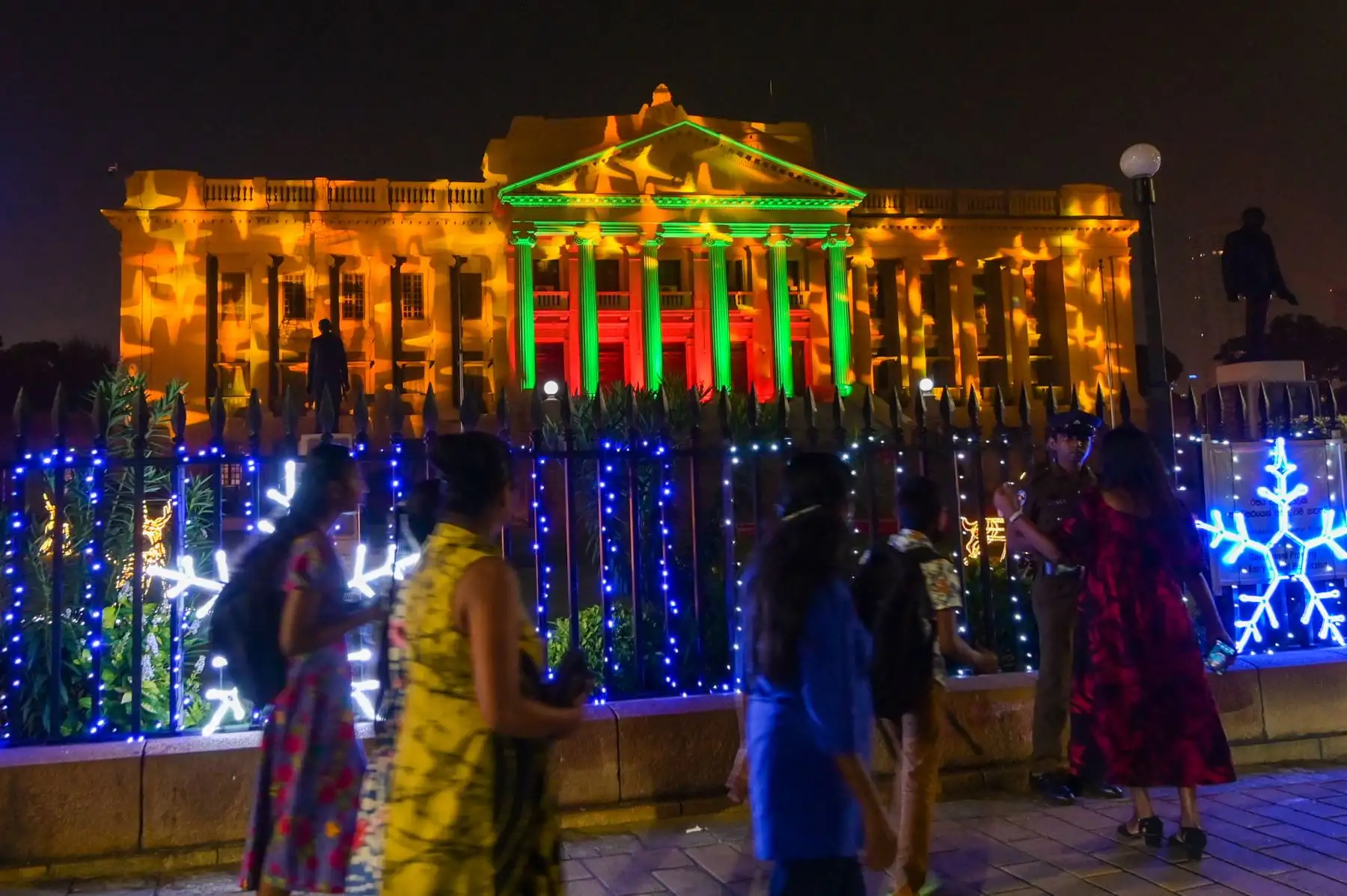 La gente pasa frente a la Secretaría Presidencial iluminada en Colombo en la víspera de Navidad. Foto: AFP
