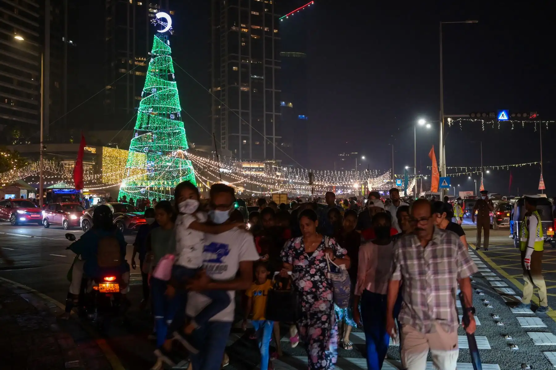 La gente camina por una calle iluminada en la víspera de Navidad, en Colombo. Foto: AFP
