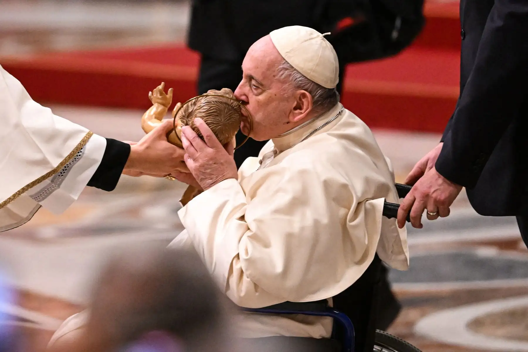 El Papa Francisco besa una figura del niño Jesús mientras asiste a la misa de Nochebuena en la Basílica de San Pedro en el Vaticano. Foto: AFP