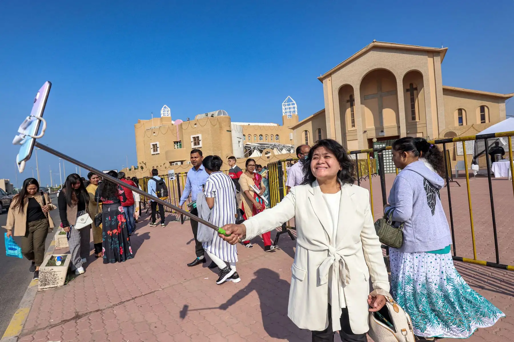 Una mujer usa un teléfono en un "palo selfie" para tomar una foto afuera de la Concatedral Católica de la Sagrada Familia en la ciudad de Kuwait. Foto: AFP
