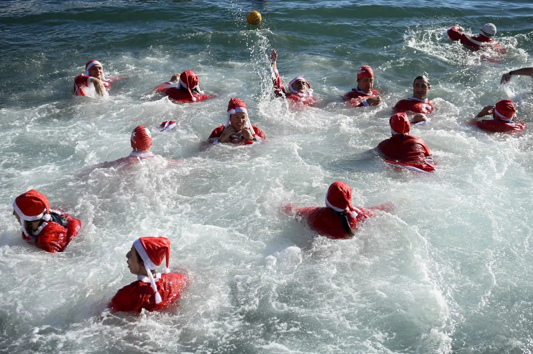 Participantes disfrazados de Papá Noel saltan al agua durante la 113ª edición de la carrera de natación Copa Nadal (Copa de Navidad) en el Port Vell de Barcelona. Foto: AFP