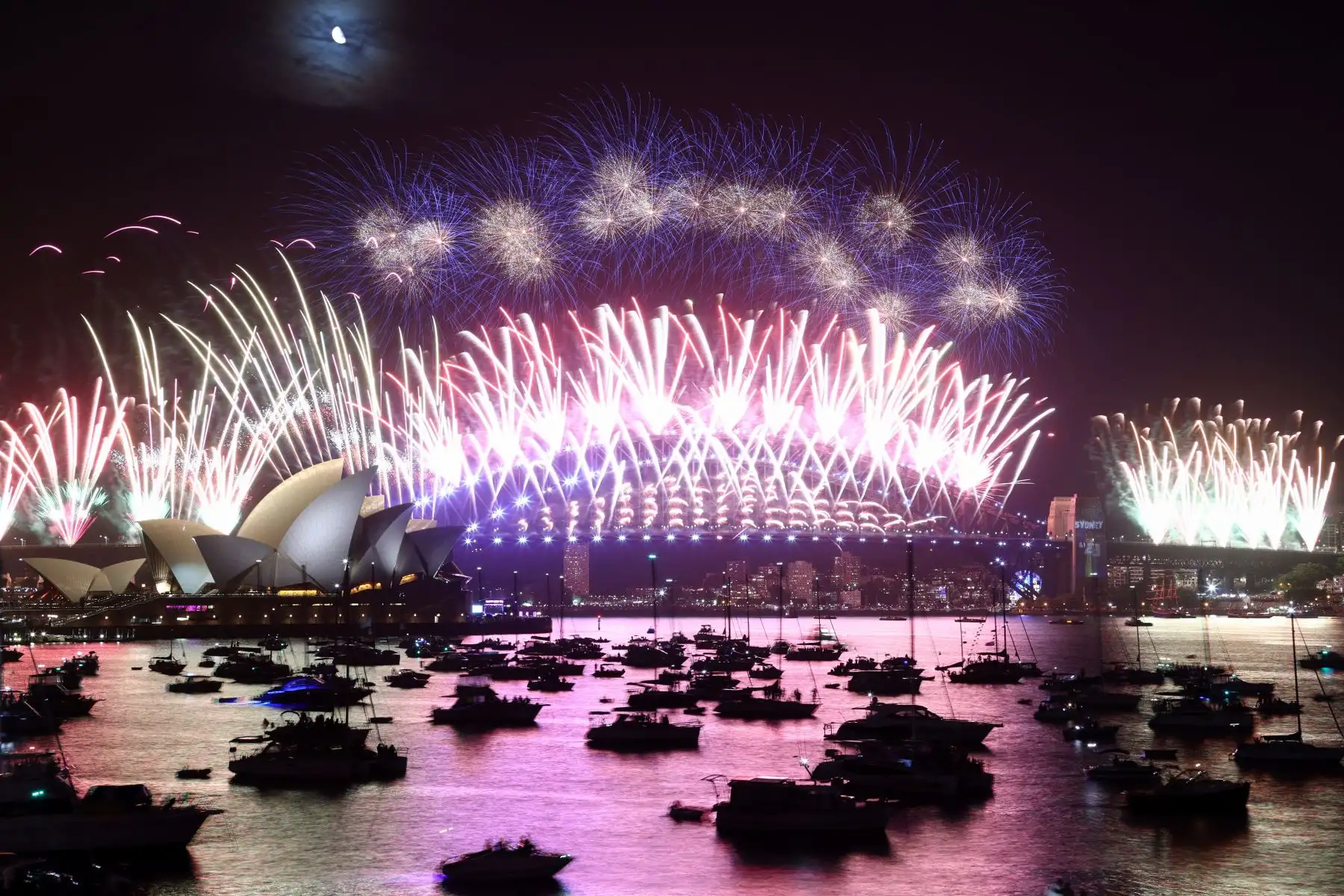Los fuegos artificiales de Nochevieja iluminan el cielo sobre la Ópera de Sídney (izq.) y el Puente Harbour durante la exhibición de fuegos artificiales en Sídney el 1 de enero de 2023. Foto: AFP