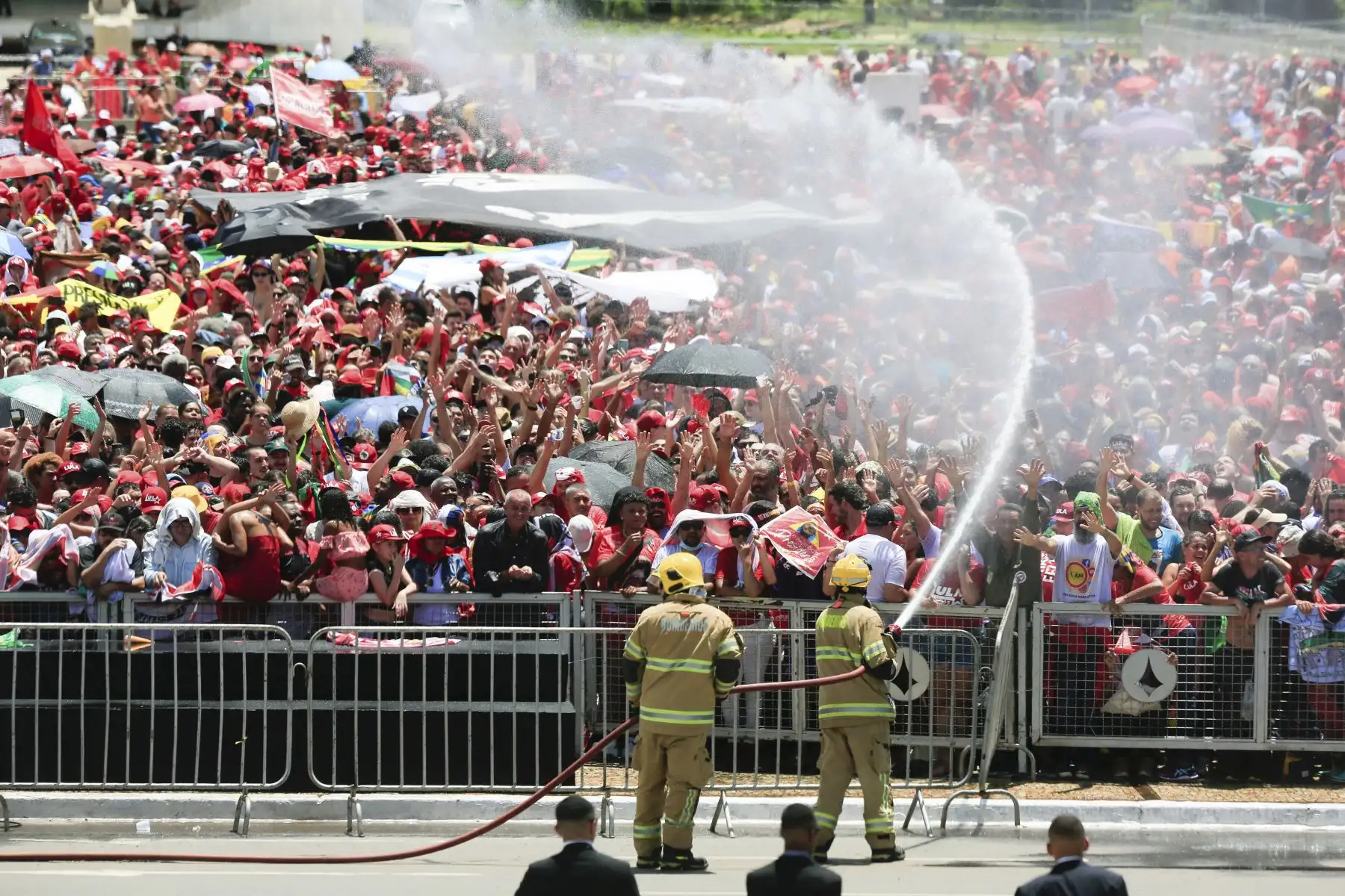 Los bomberos rocían agua para aliviar del calor a los partidarios del presidente electo Luiz Inácio Lula da Silva mientras se reúnen para esperar su ceremonia de toma de posesión en la plaza "Tres Poderes" frente al Palacio Planalto en Brasilia, el 1 de enero de 2023.  Lula da Silva, un izquierdista de 77 años. Foto: AFP