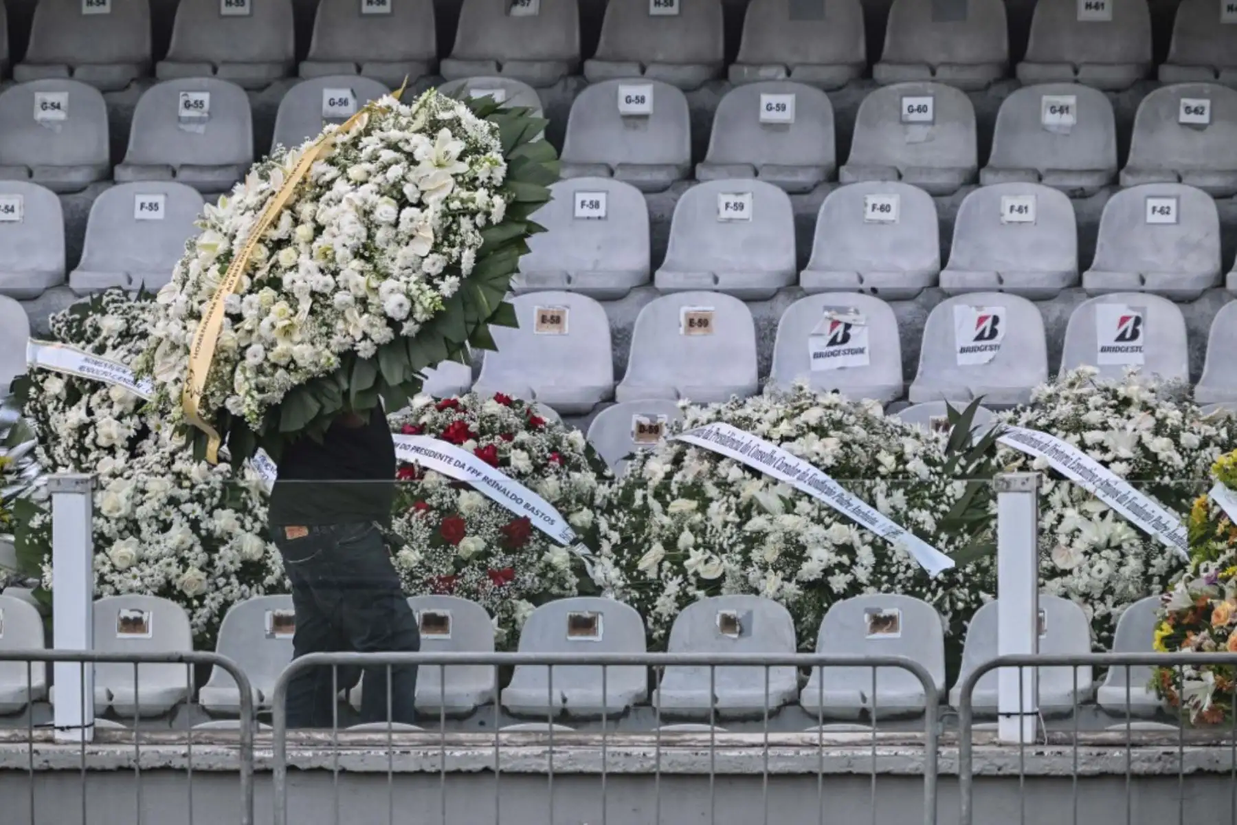 Un hombre lleva una corona de flores dentro del estadio Vila Belmiro antes del inicio del velorio de la leyenda del fútbol brasileño Pelé en Santos, en Sao Paulo. Foto: AFP
