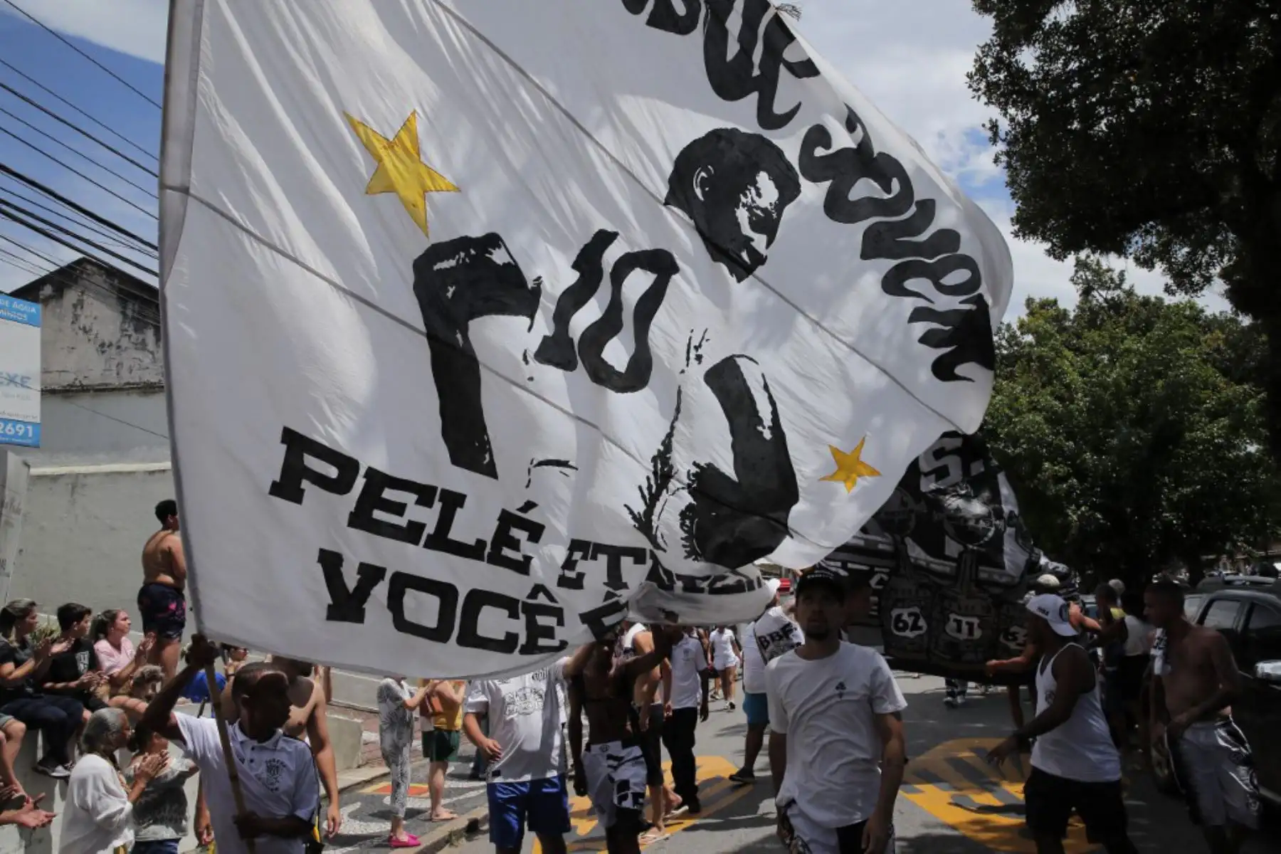 Fanáticos de la difunta estrella del fútbol brasileño Pelé se reúnen en la calle mientras un camión de bomberos transporta el ataúd de Pelé al Cementerio Conmemorativo de Santos en Santos, estado de Sao Paulo, Brasil. Foto: AFP