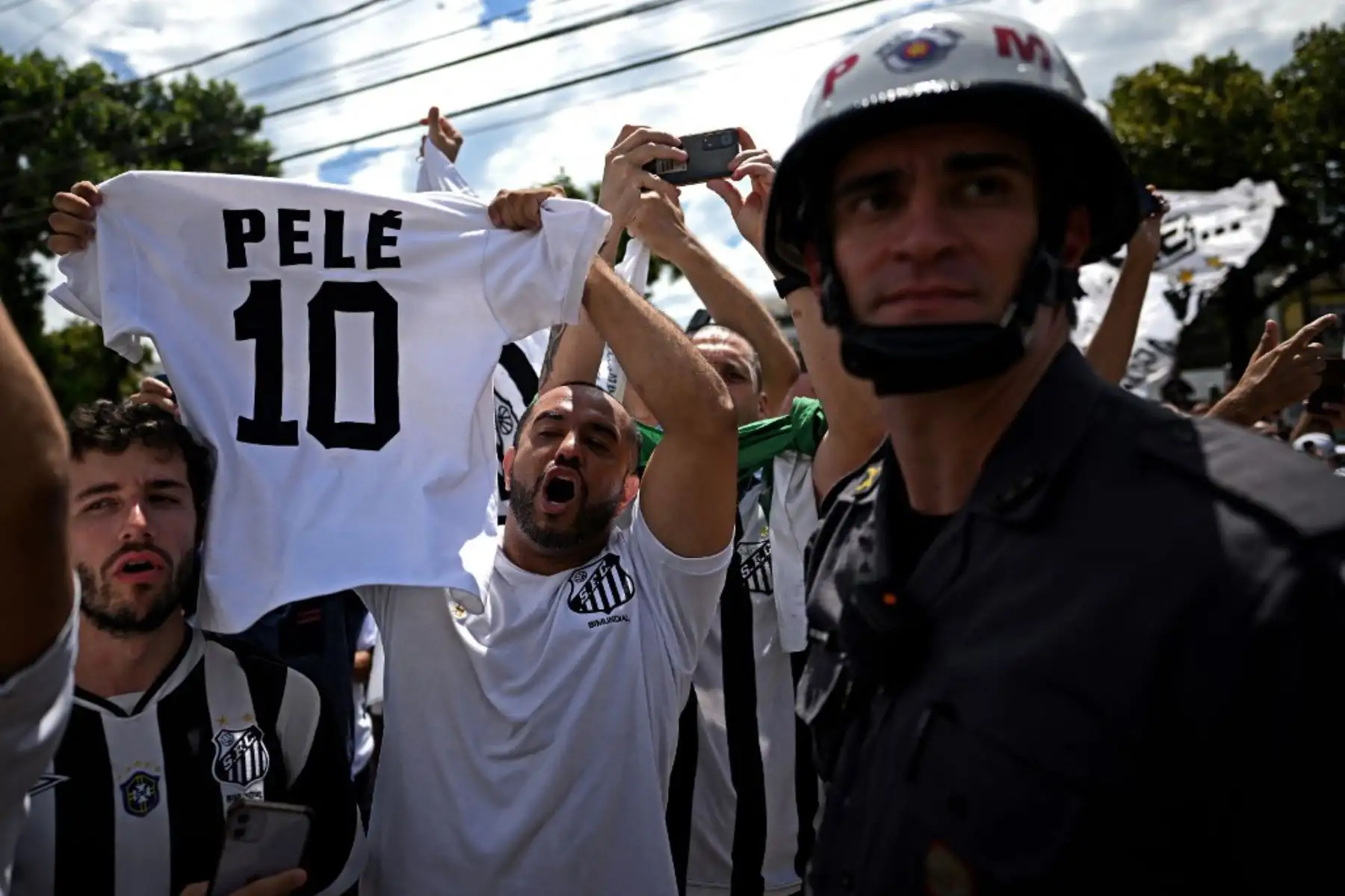 Fanáticos de la difunta estrella del fútbol brasileño Pelé se reúnen en la calle mientras un camión de bomberos transporta el ataúd de Pelé al Cementerio Conmemorativo de Santos en Santos, estado de Sao Paulo, Brasil. Foto: AFP