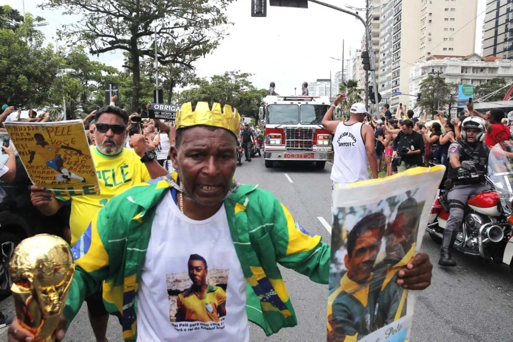 Los fanáticos de Pelé se reúnen en la calle mientras un camión de bomberos transporta el ataúd al Cementerio Conmemorativo de Santos en Santos, estado de Sao Paulo, Brasil. Foto: AFP