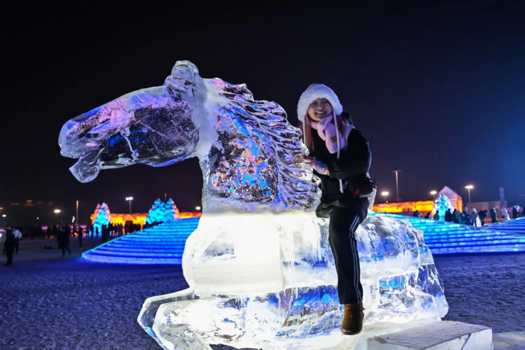 Una mujer posa sentada en un caballo de hielo en el Mundo de Hielo y Nieve de Harbin en Harbin, en la provincia nororiental china de Heilongjiang. Foto: AFP