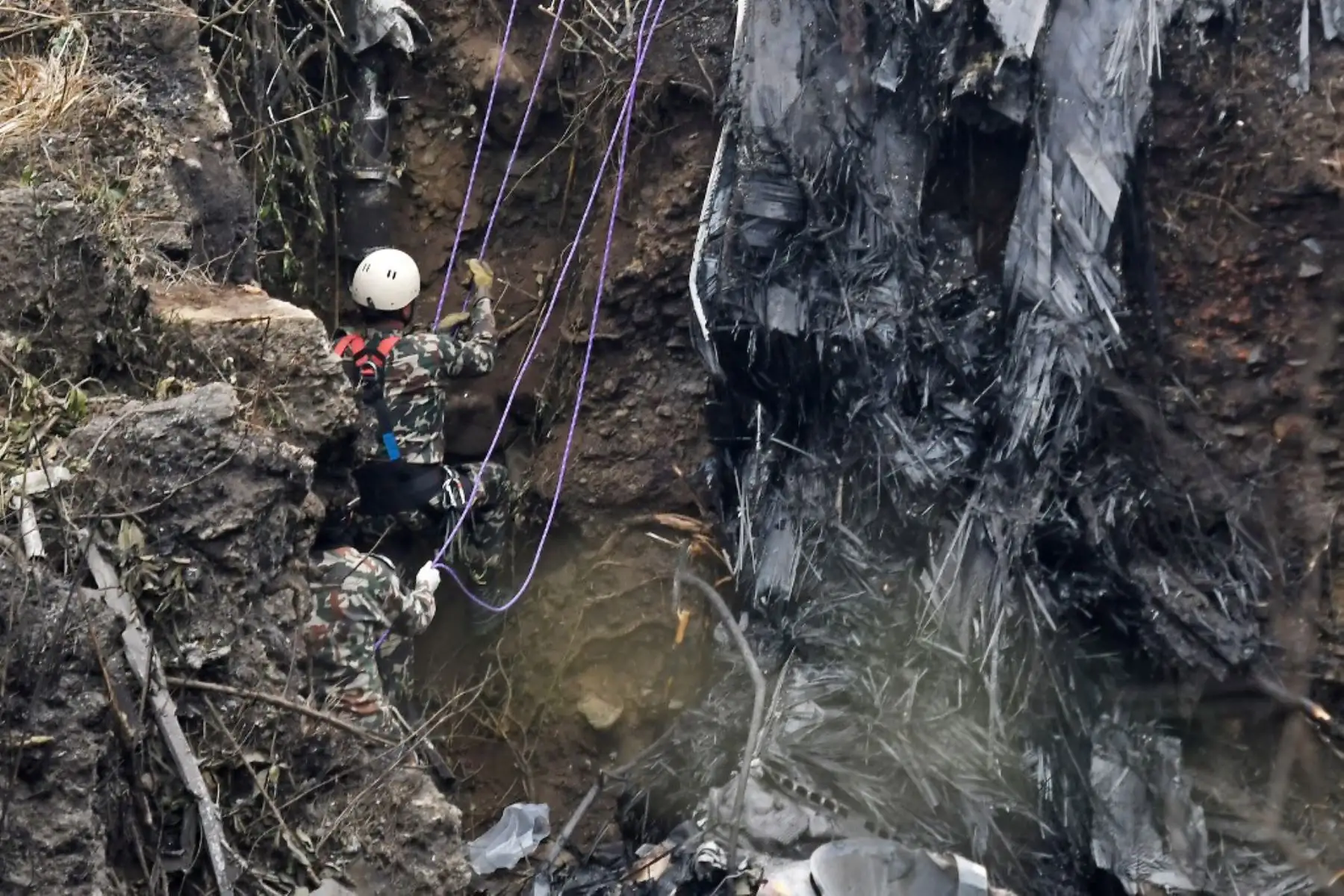 Rescatistas inspeccionan los restos en el lugar donde se estrelló un avión de Yeti Airlines en Pokhara. Foto: AFP