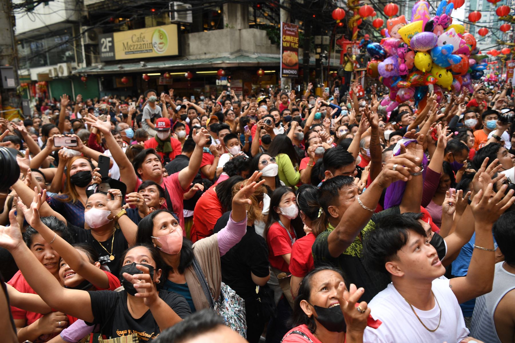 Las personas intentan atrapar el lai see (sobre rojo) y las golosinas que arrojan los empleados de una tienda de comestibles durante las celebraciones del año nuevo lunar en el área de Chinatown de Manila el 22 de enero de 2023.
Foto: AFP