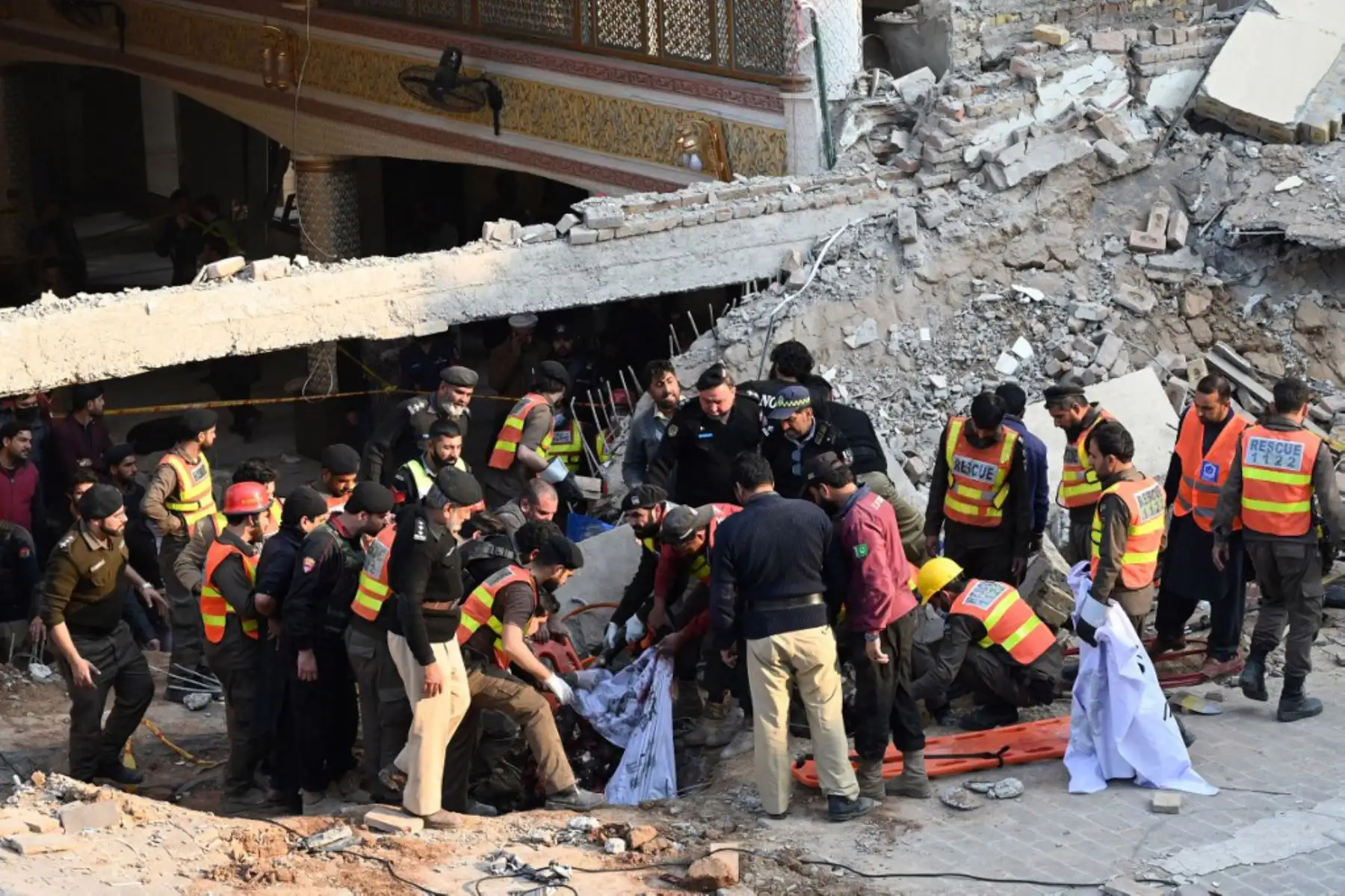 Personal de seguridad y rescatistas buscan víctimas de la explosión entre los escombros de una mezquita en Peshawar. Foto: AFP