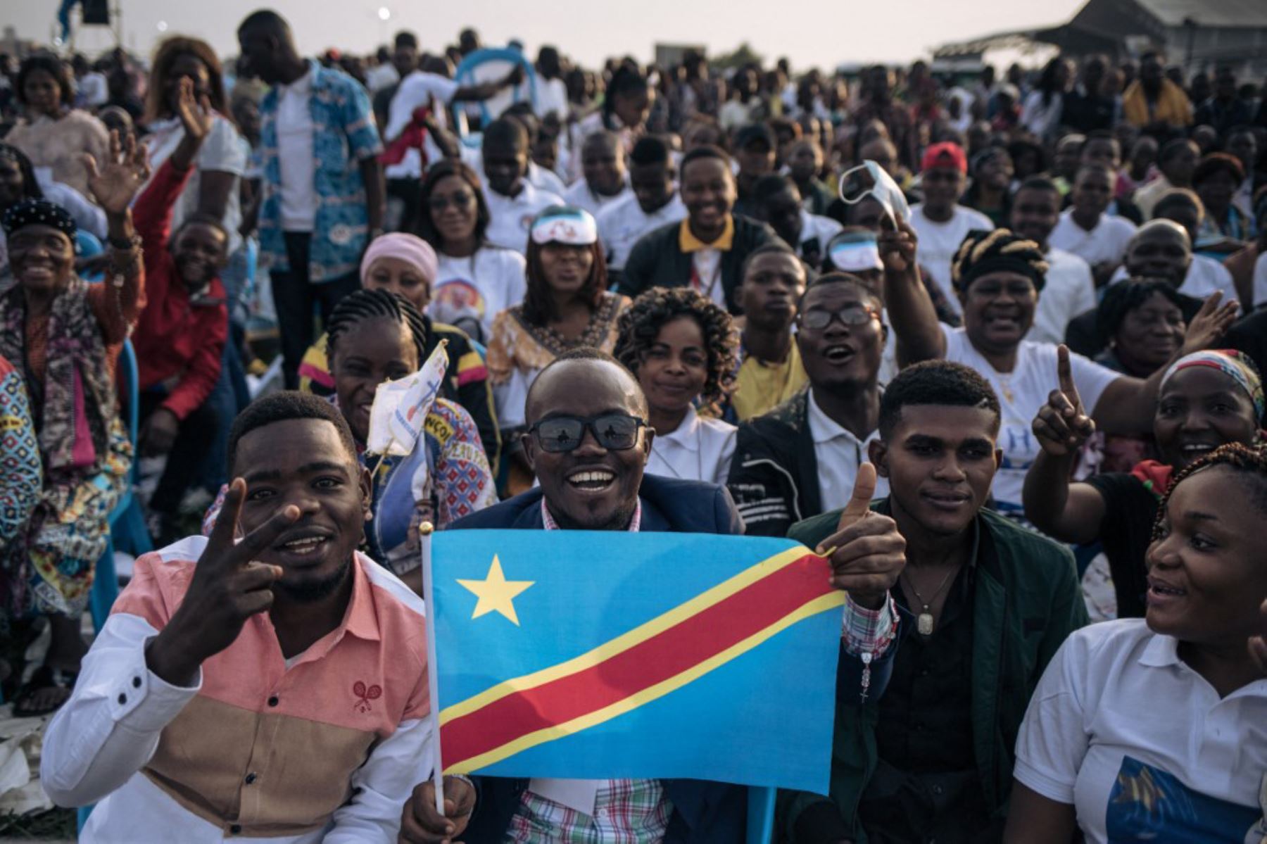 Un hombre sostiene una bandera de la República Democrática del Congo mientras los asistentes se reúnen antes de la llegada del Papa Francisco en el Congo. Foto: AFP