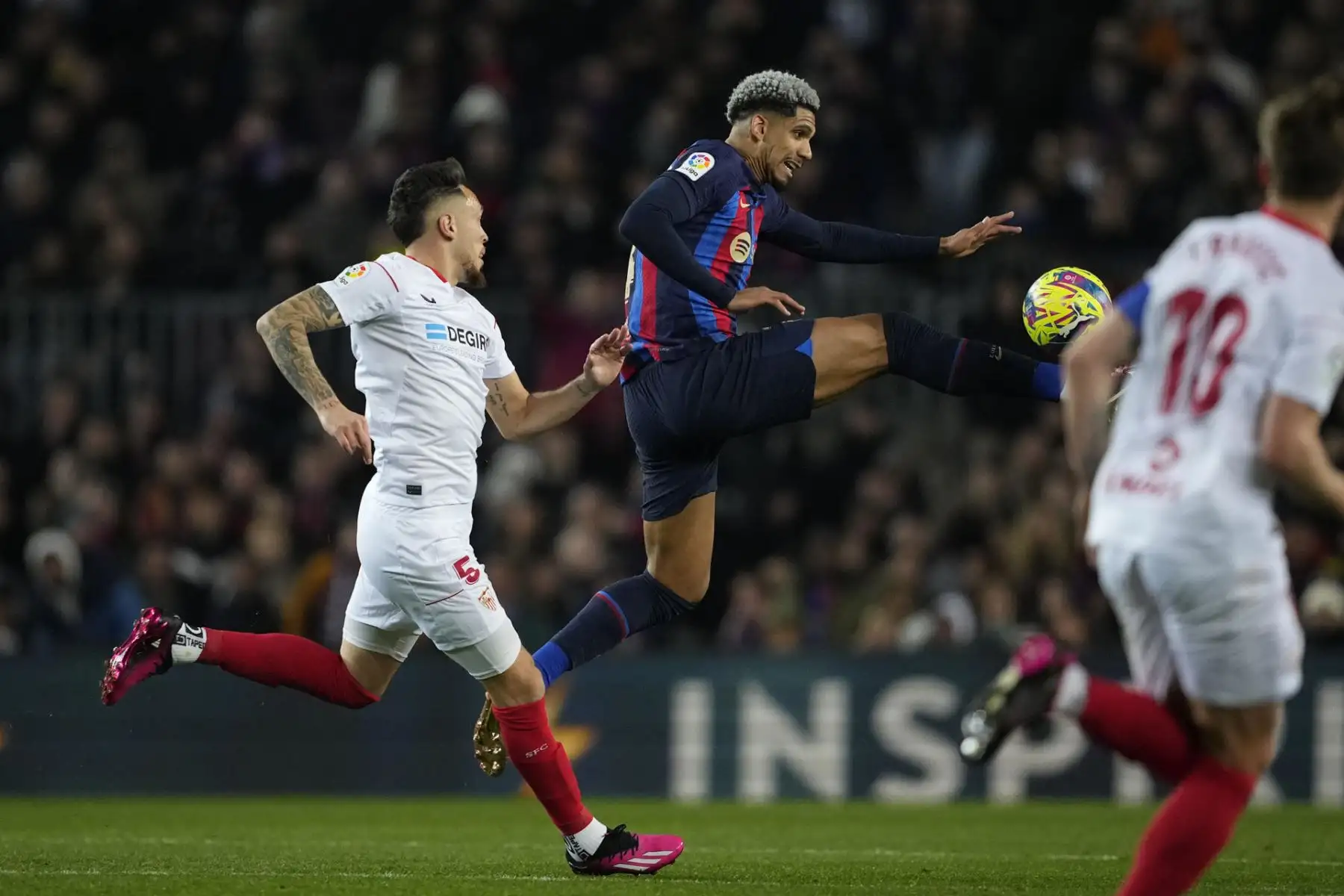 Ronald Araújo (c), defensa del FC Barcelona disputa un balón con el delantero argentino del Sevilla, Lucas Campos (i) durante el partido de la jornada 20 de LaLiga que FC Barcelona y Sevilla FC disputan hoy domingo en el Camp Nou.

Foto: EFE