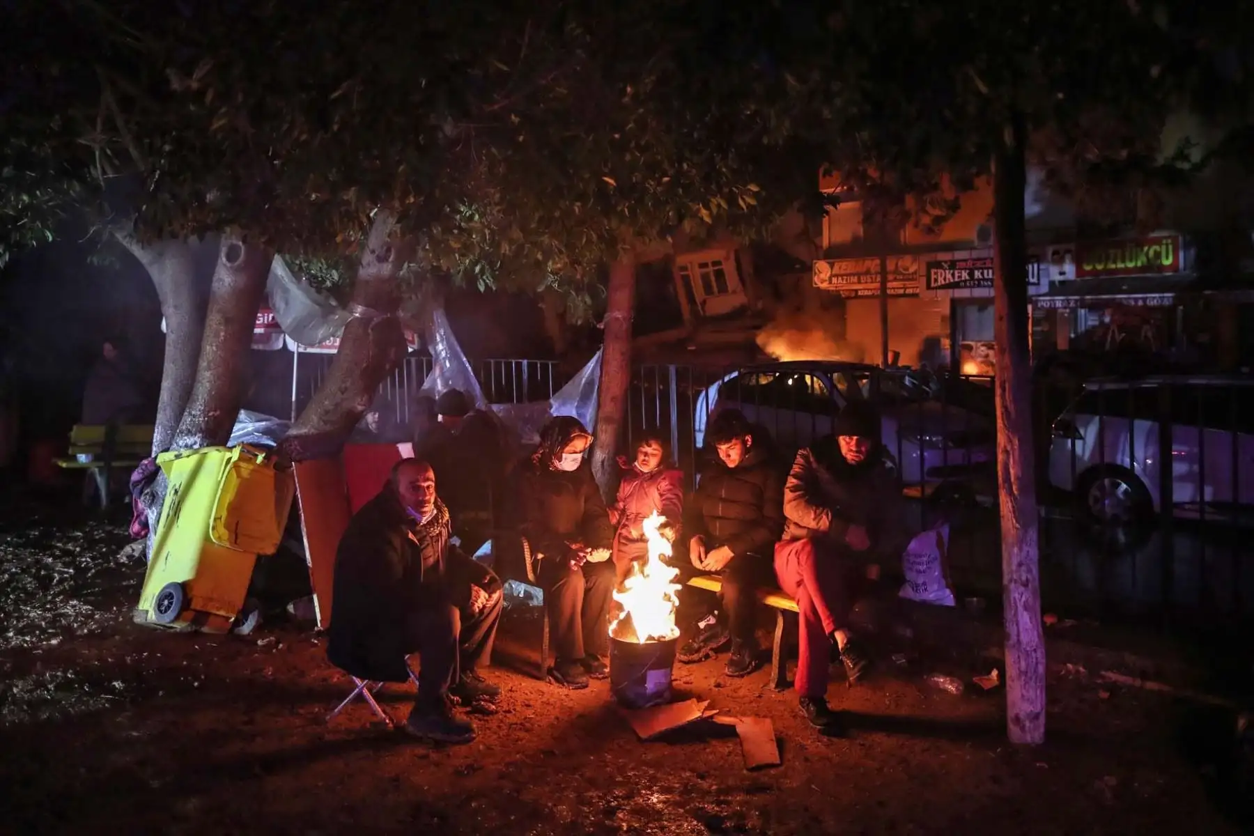 La gente se calienta alrededor de un fuego mientras el personal de emergencia busca víctimas en el sitio de un edificio derrumbado después de un terremoto en el distrito de Iskenderun de Hatay, Turquía. Foto:AFP