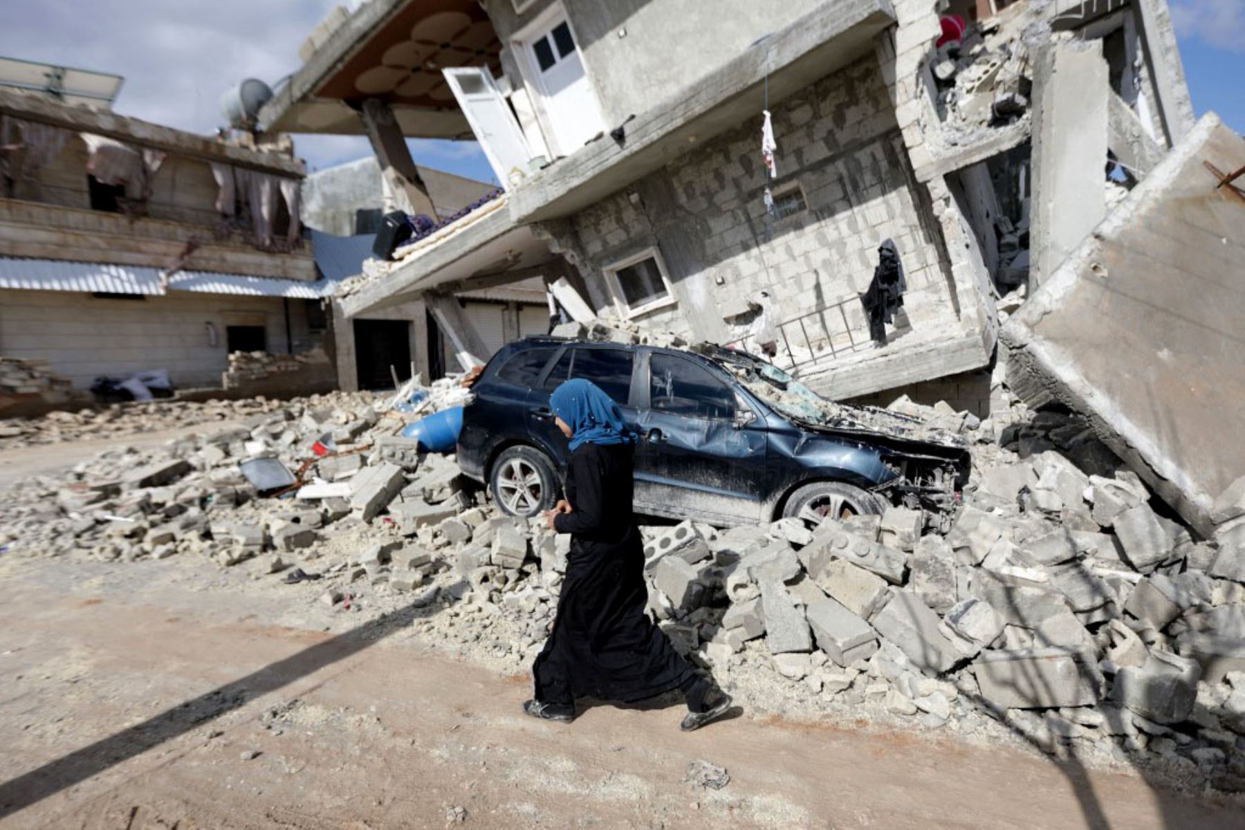 Una mujer siria pasa frente a una casa medio derrumbada en la ciudad de Azaz, en la frontera con Turquía. Foto: AFP