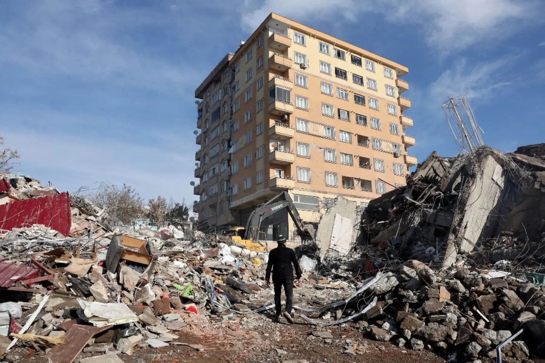 Un hombre camina sobre los escombros de un edificio derrumbado hacia un edificio que sigue en pie en Kahramanmaras, cerca del epicentro del terremoto. Foto: AFP