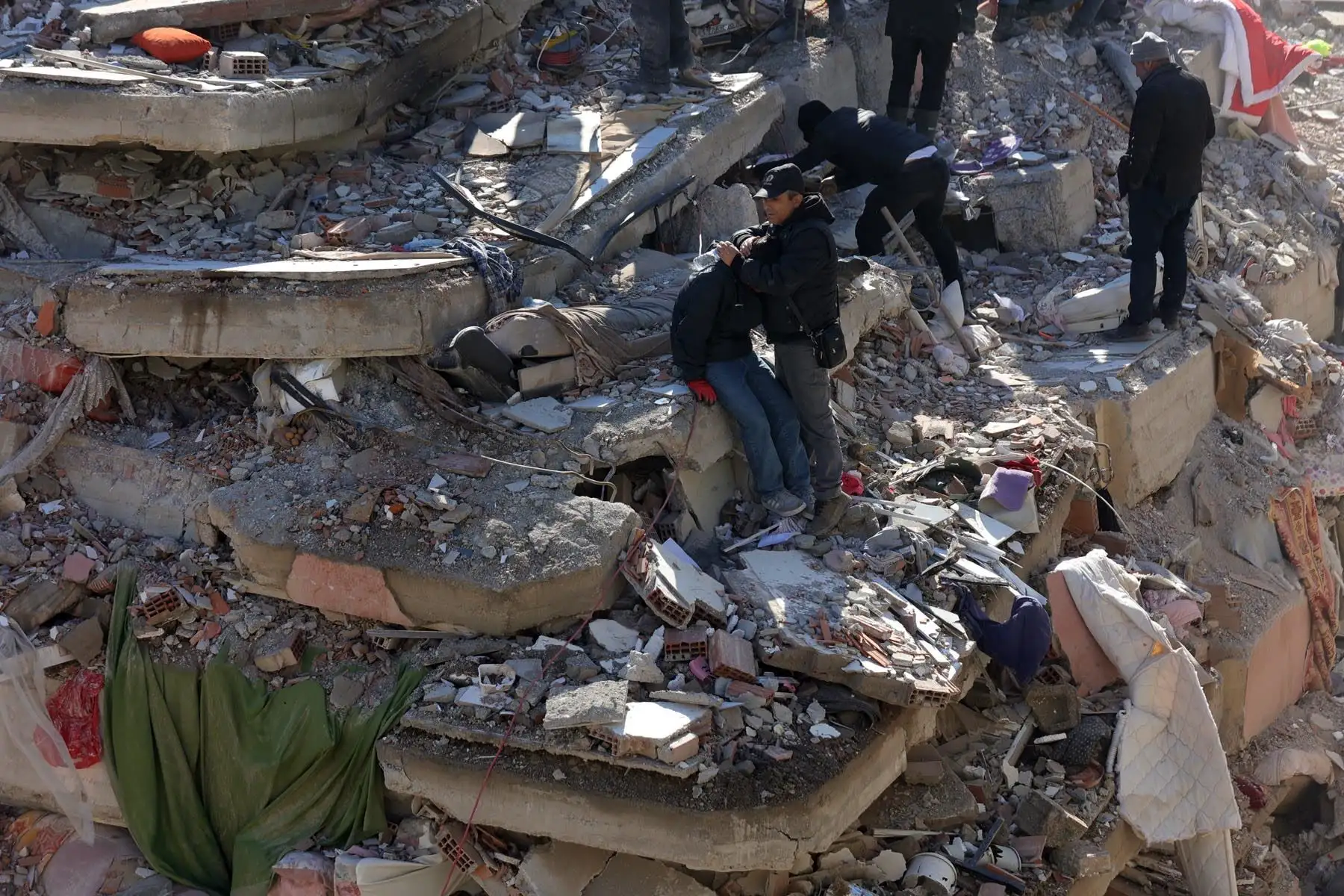 Gente ante los escombros de un edificio derrumbado en la ciudad de Kahramanmaras, sureste de Turquía. Foto: AFP
