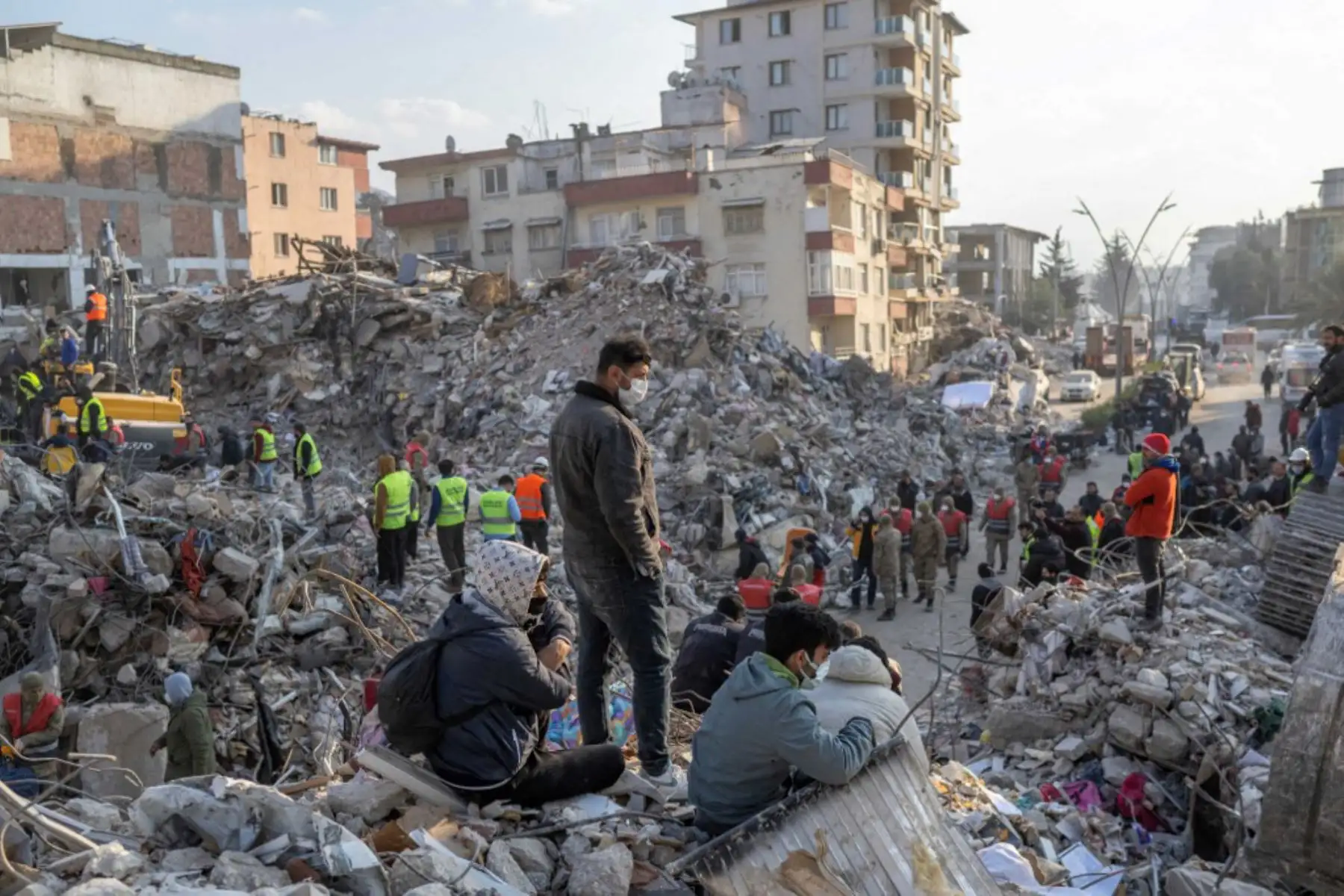 Las personas se paran sobre los escombros de los edificios derrumbados durante las operaciones de rescate en Hatay. Foto: AFP