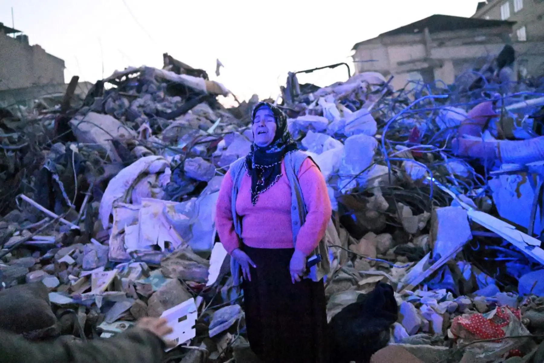 Una mujer camina entre los escombros de los edificios derrumbados en Hatay, cuando los equipos de rescate comenzaron a reducir la búsqueda de sobrevivientes, una semana después de que un terremoto devastara partes de Turquía y Siria. Foto: AFP