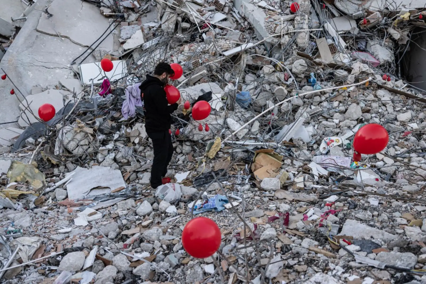 Globos rojos revolotean, colgando de las ruinas. Son "los últimos juguetes" de los niños fallecidos durante el terremoto que asoló esta ciudad del sur de Turquía, explica Ogun Sever Okur, autor de este regalo póstumo. Foto: AFP