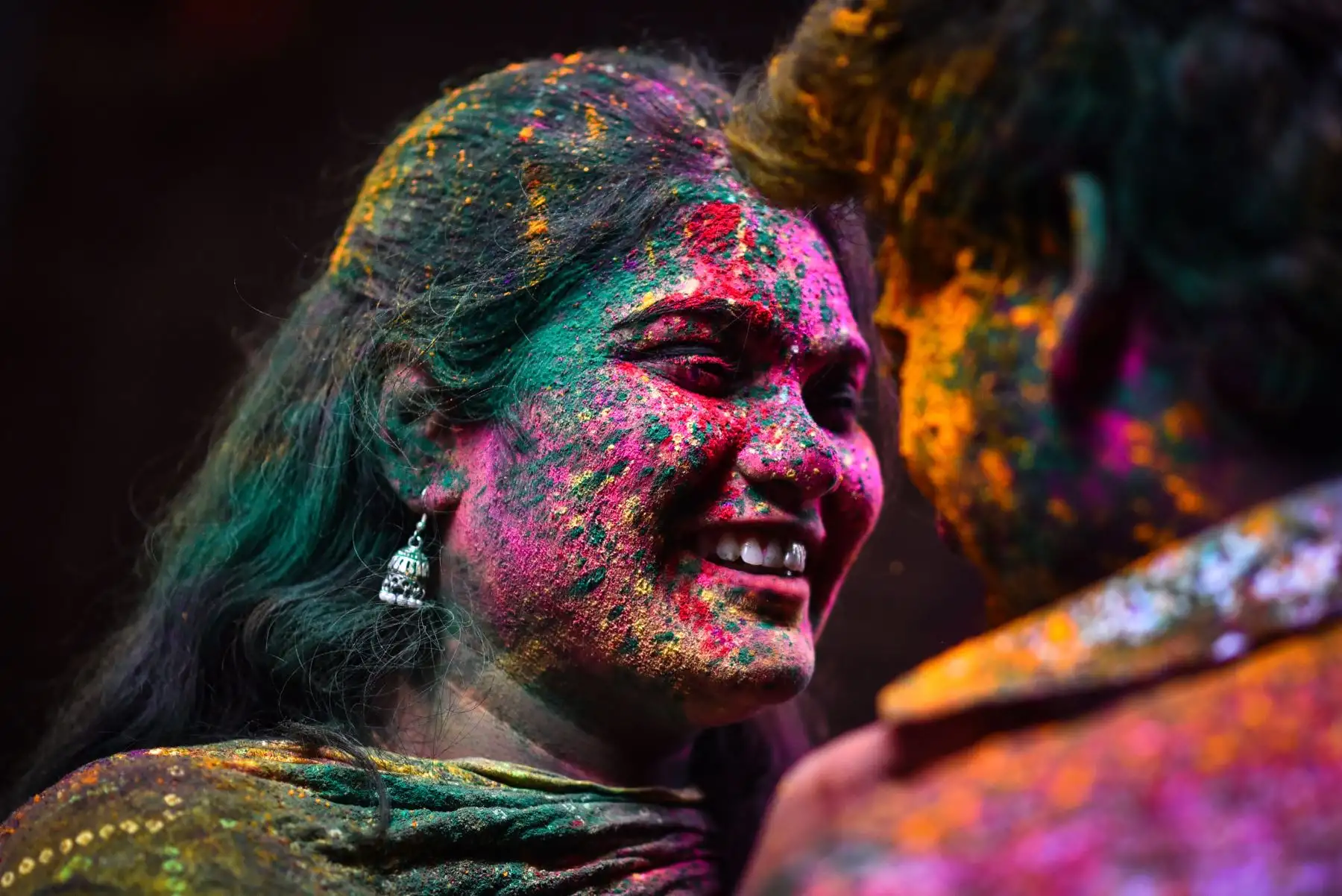 Una mujer manchada con polvo coloreado reacciona durante las celebraciones del festival Holi en Chennai, India, el 8 de marzo de 2023. Holi, también conocido como el 