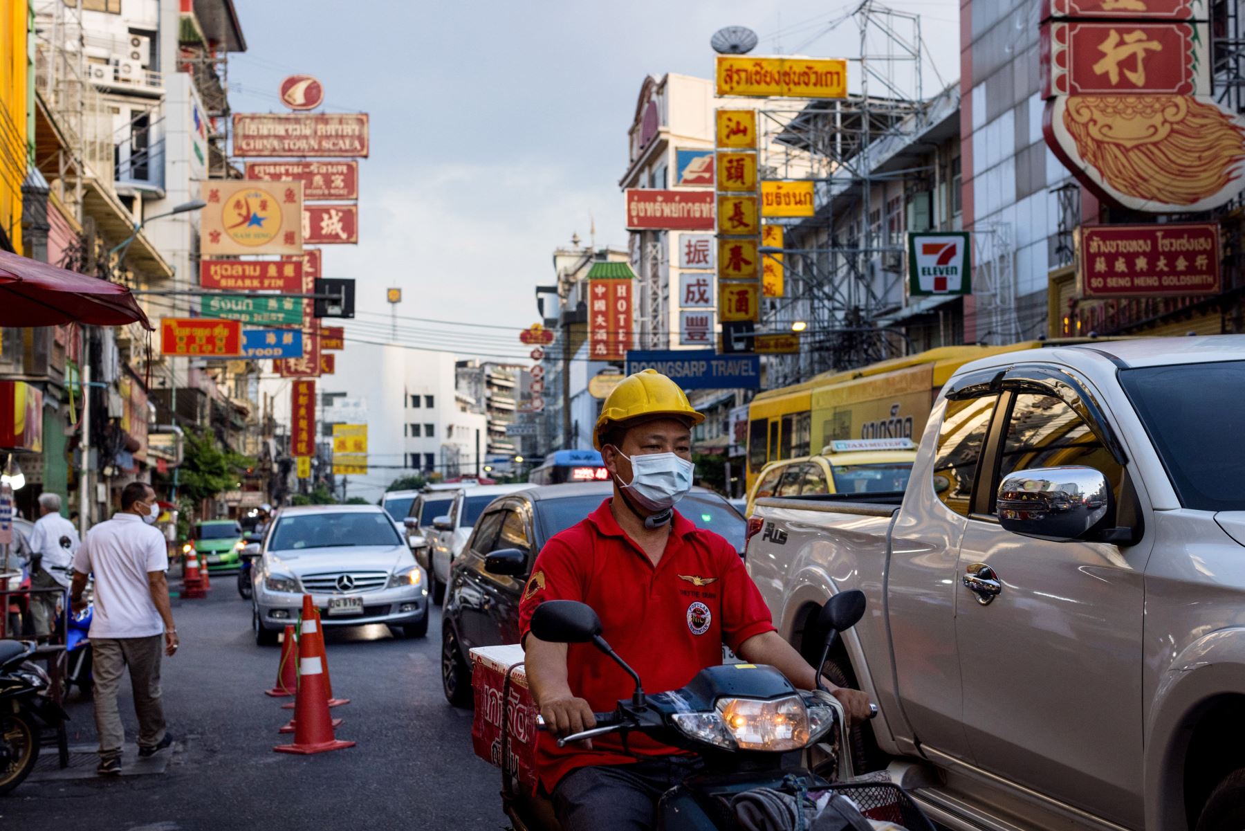 Un hombre con casco y mascarilla conduce una motocicleta por el barrio chino de Bangkok el 4 de enero de 2022. Foto: AFP