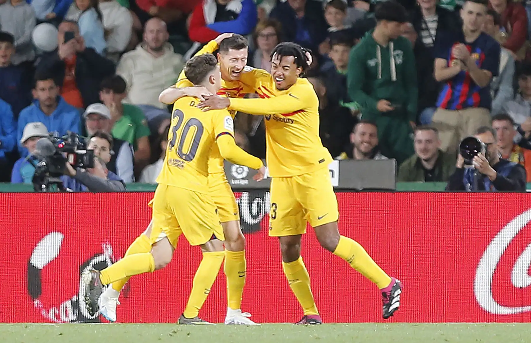 El delantero polaco del Barcelona Robert Lewandowski (C) celebra con el centrocampista español del Barcelona Gavi (L) y el defensa francés del Barcelona Jules Kounde el tercer gol de su equipo durante el partido de fútbol de la liga española entre el Elche CF y el FC Barcelona en el estadio Martínez Valero de Elche. Foto: AFP