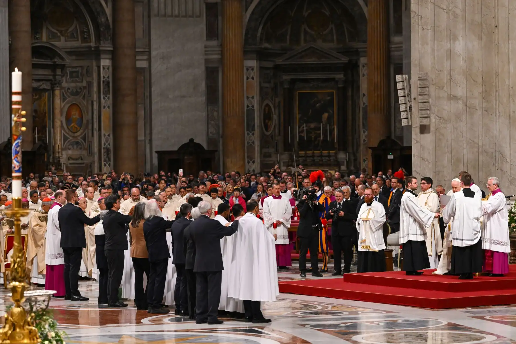 Los ocho catecúmenos recién bautizados, vestidos con una túnica blanca y escoltados por sus respectivas madrinas o padrinos, se preparan para recibir el sacramento de la Confirmación de manos del Papa Francisco durante la misa de la Vigilia Pascual, en San Pedro basílica del Vaticano, como parte de las celebraciones de la Semana Santa. Foto: AFP