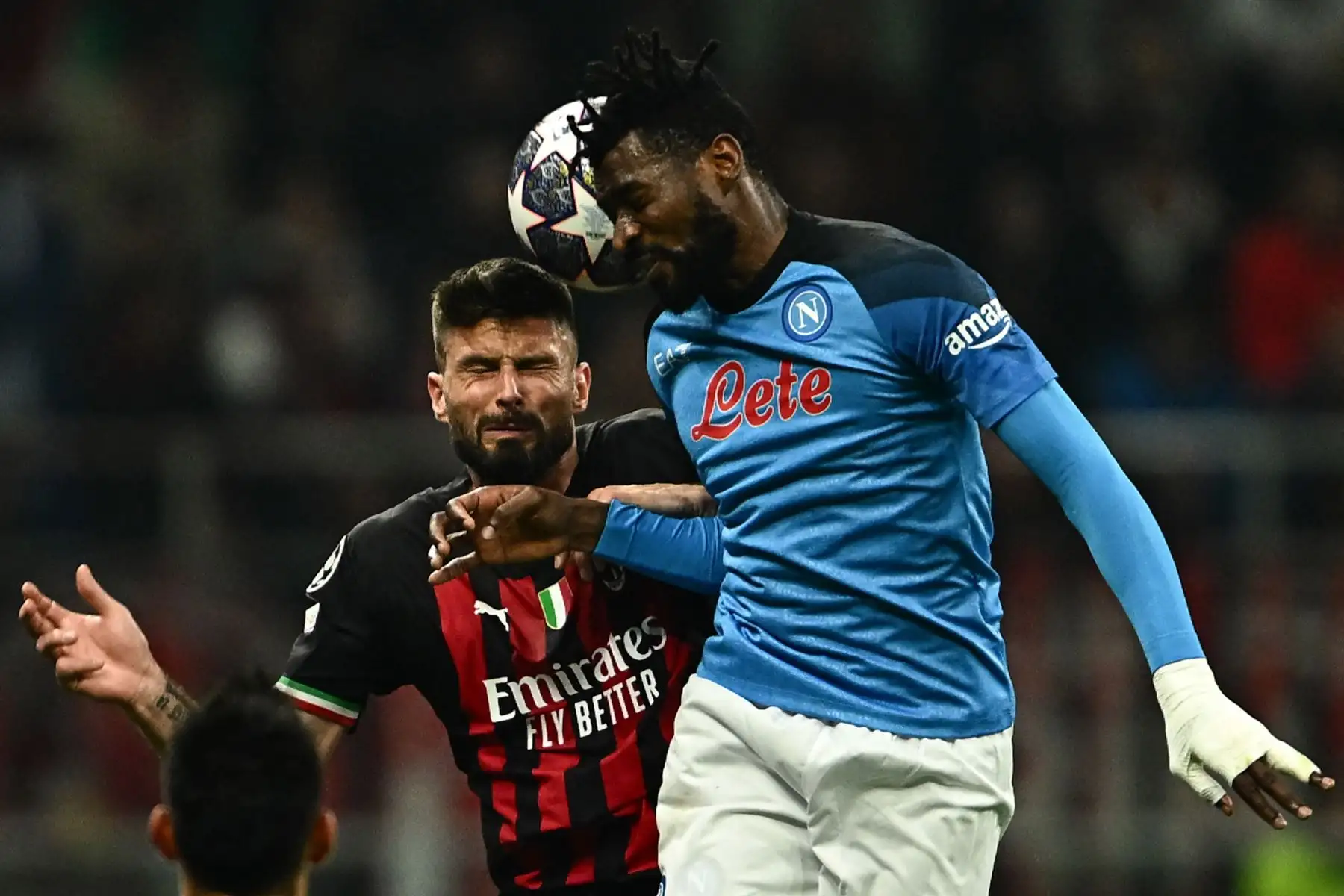 El delantero francés del AC Milan, Olivier Giroud, y el centrocampista camerunés del Napoli, Andre Zambo Anguissa, van a por un cabezazo durante el partido de ida de los cuartos de final de la Liga de Campeones de la UEFA entre el AC Milan y el SSC Napoli. Foto: AFP
