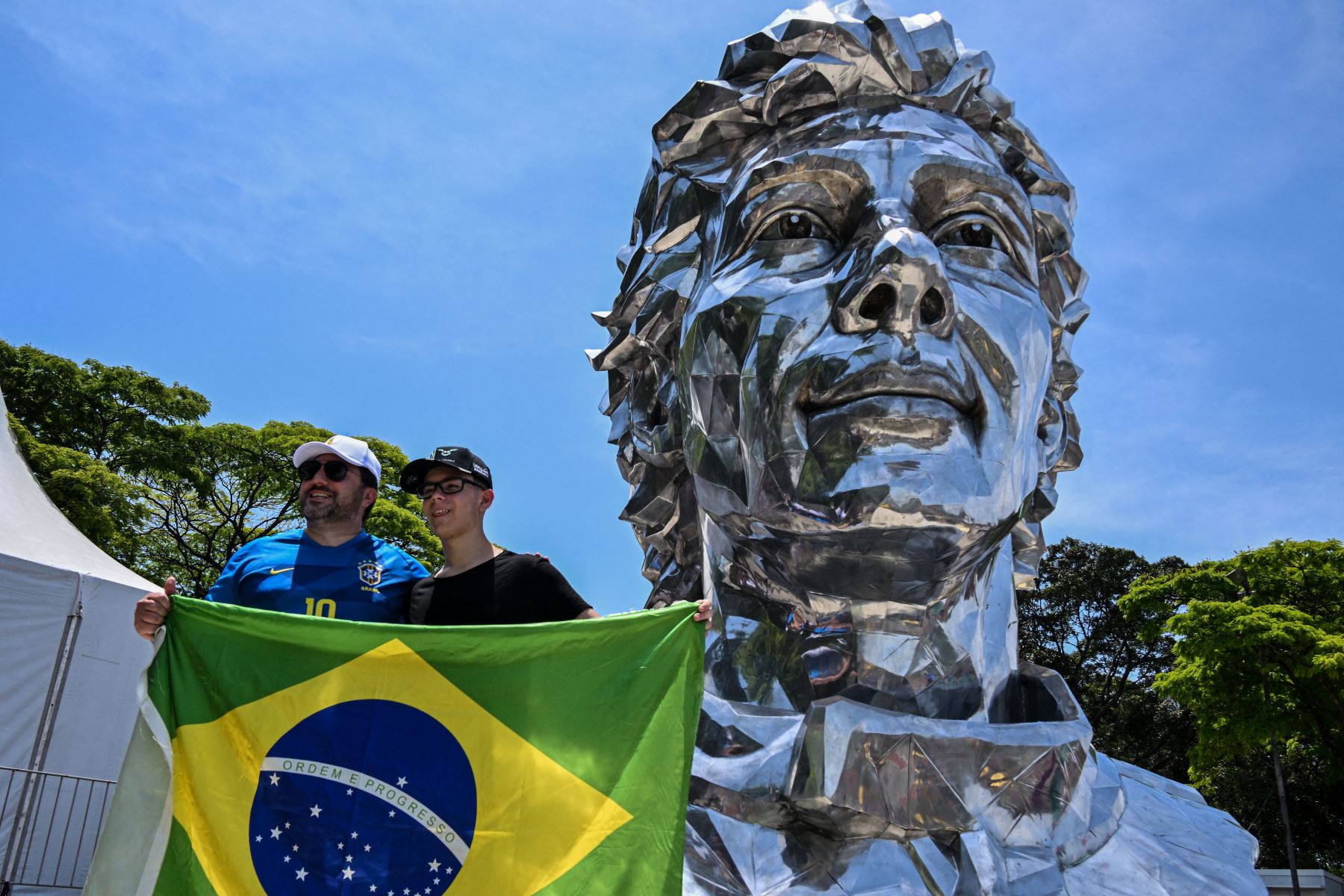 Los fanáticos de la F1 posan para una foto frente a una escultura del difunto piloto brasileño de F1 Ayrton Senna en el autódromo José Carlos Pace, en Sao Paulo, Brasil, el 13 de noviembre del 2022. Foto: AFP