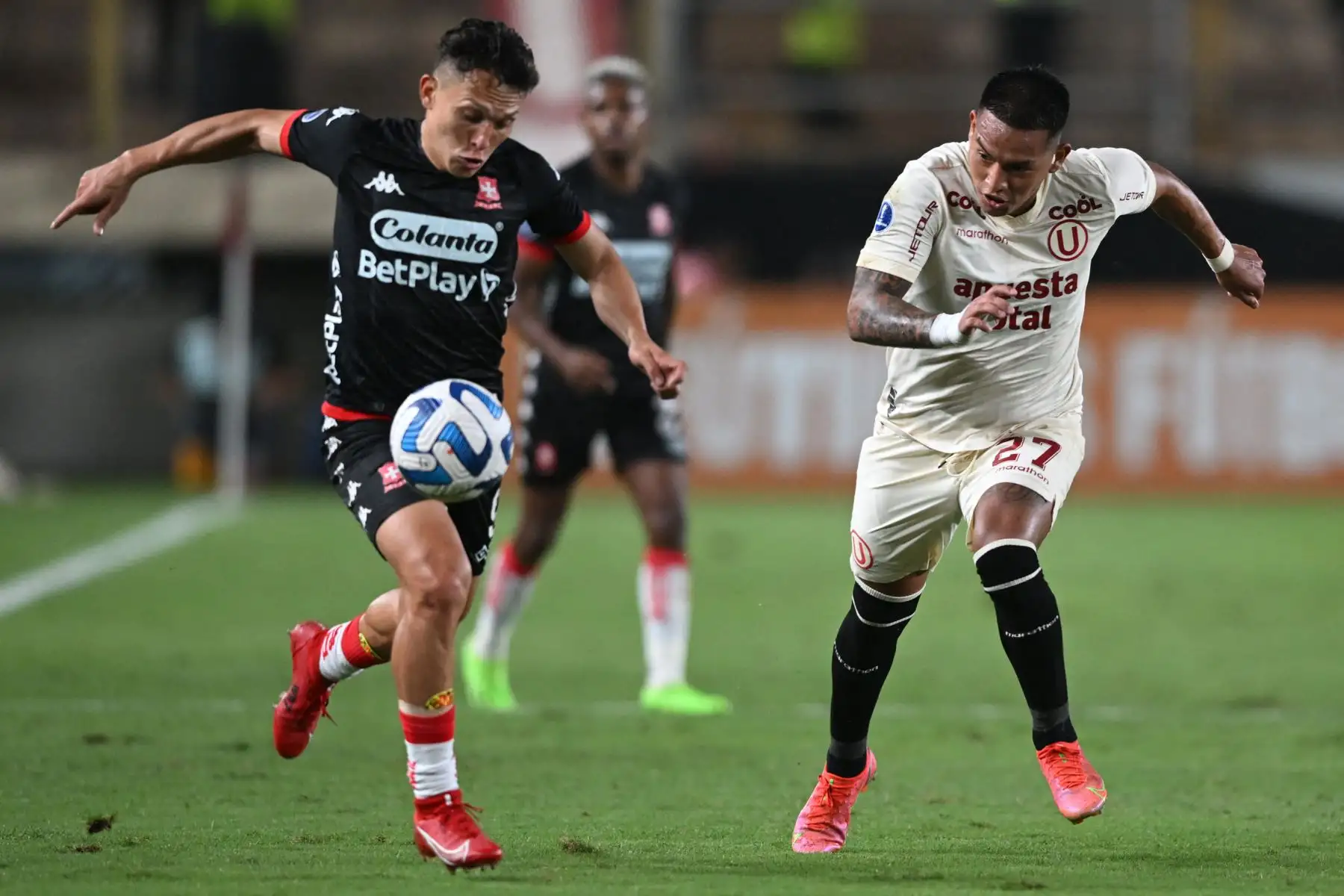 El delantero de Santa Fe Wilfrido De La Rosa  y el defensa de Universitario Nelson Cabanillas disputan el balón durante el partido de ida de la fase de grupos de la Copa Sudamericana entre Universitario de Perú e Independiente Santa Fe de Colombia, en el estadio Monumental de Ate. Foto:ANDINA/ AFP