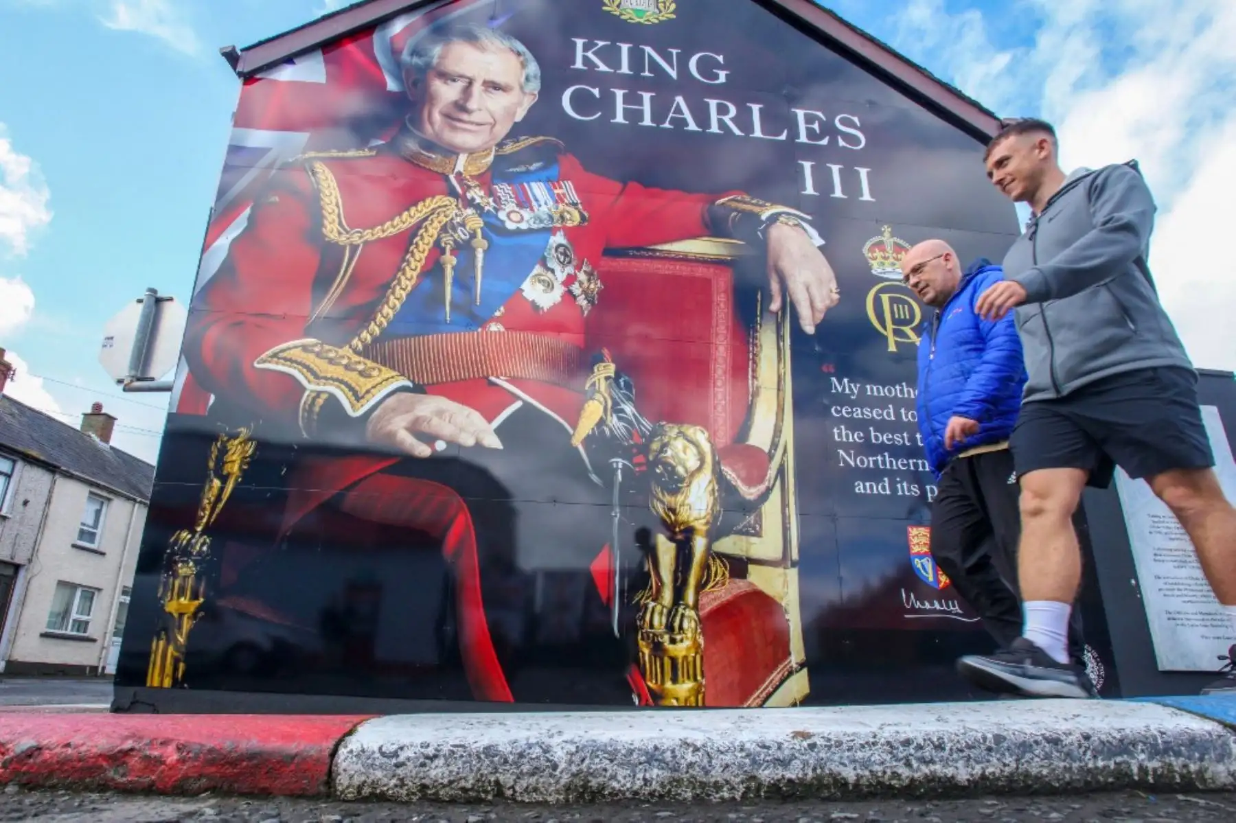 Los miembros del público pasan frente a un nuevo mural del rey Carlos III de Gran Bretaña en Larne, al norte de Belfast en Irlanda del Norte el 5 de mayo de 2023, en la preparación para el fin de semana de coronación. Foto. AFP