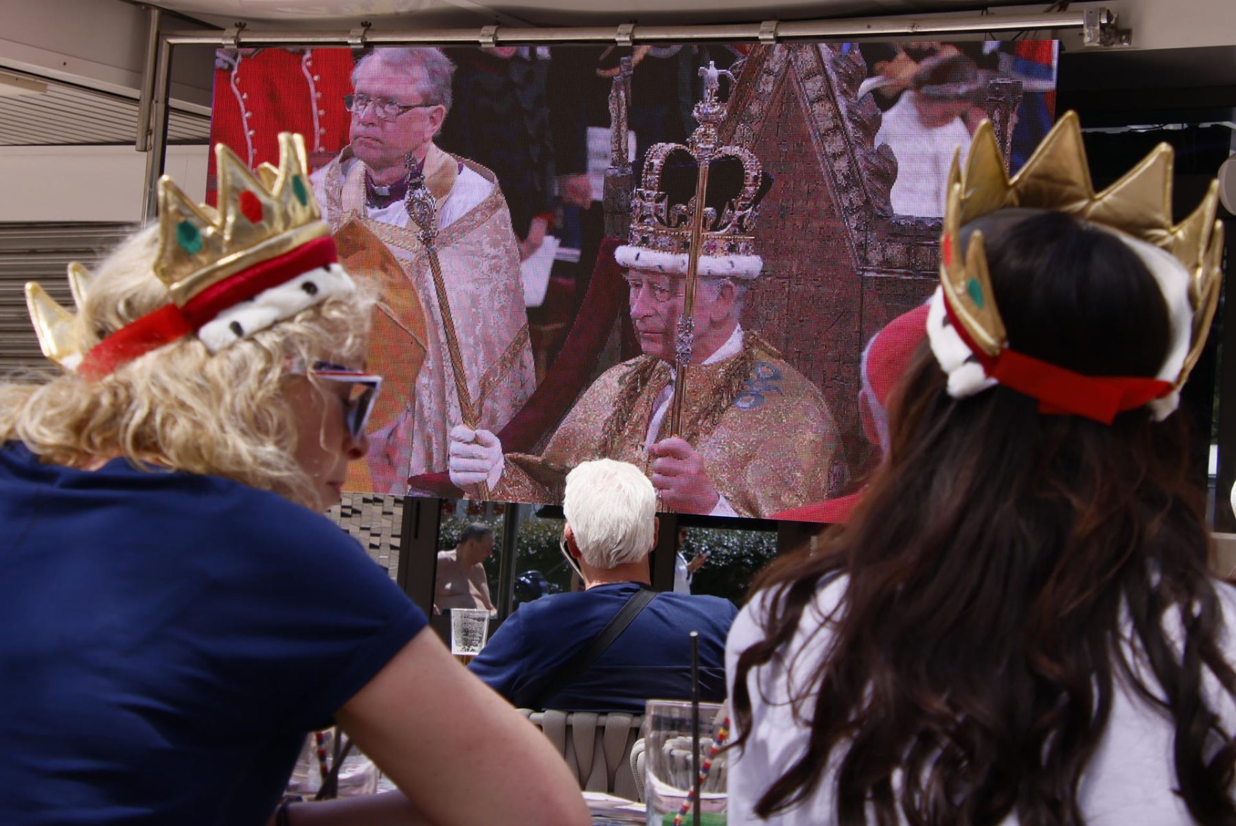Un grupo de turistas británicos este sábado en Magaluf (Calviá, Baleares), sigue en directo la coronación del rey Carlos III, con coronas de juguete en la cabeza.
Foto: AFP