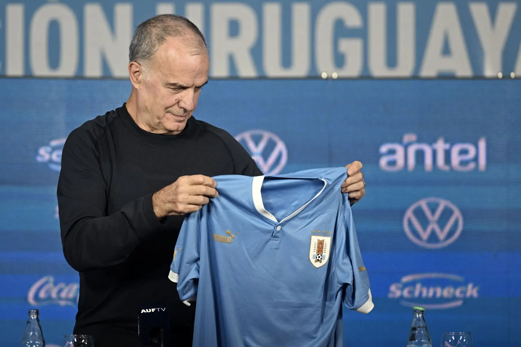 El argentino Marcelo Bielsa mira una camiseta de la selección de fútbol de Uruguay con su nombre durante su presentación como entrenador del equipo, en el Estadio Centenario de Montevideo, el 17 de mayo de 2023. 
Foto: AFP