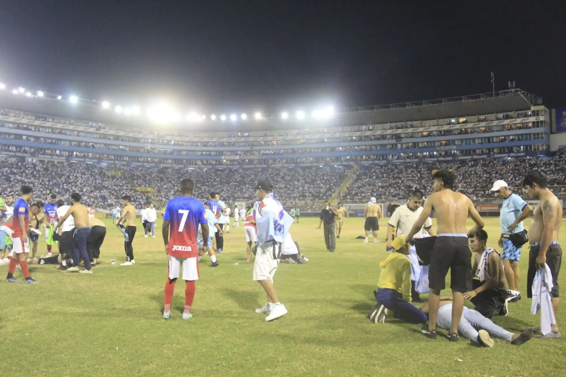 Jugadores y fanáticos asisten a heridos tirados en la cancha luego de una estampida durante un partido de fútbol entre Alianza y FAS en el estadio Cuscatlán en San Salvador. Foto:ANDINA/ AFP