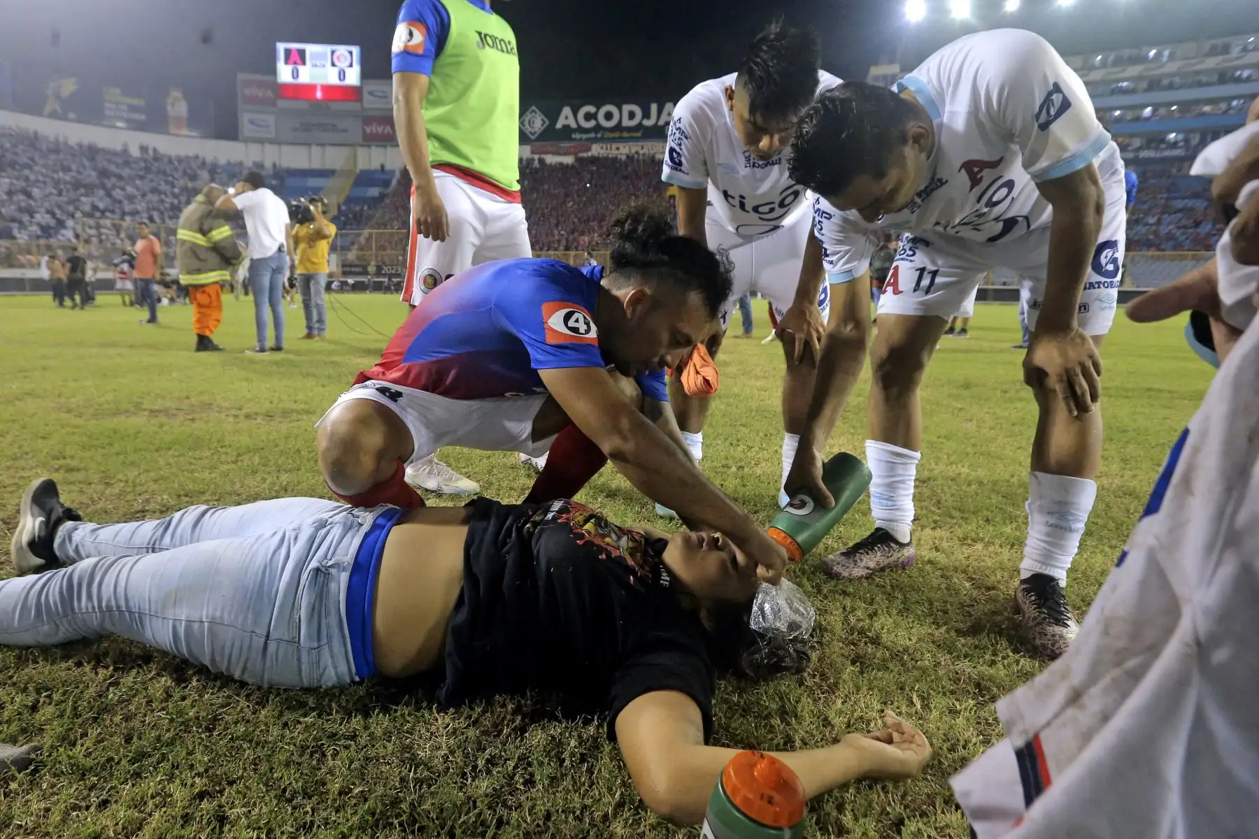 Jugadores de Alianza atienden a un aficionado herido tirado en la cancha luego de una estampida durante un partido de fútbol entre Alianza y FAS en el estadio Cuscatlán en San Salvador. Nueve personas murieron. Foto:ANDINA/AFP