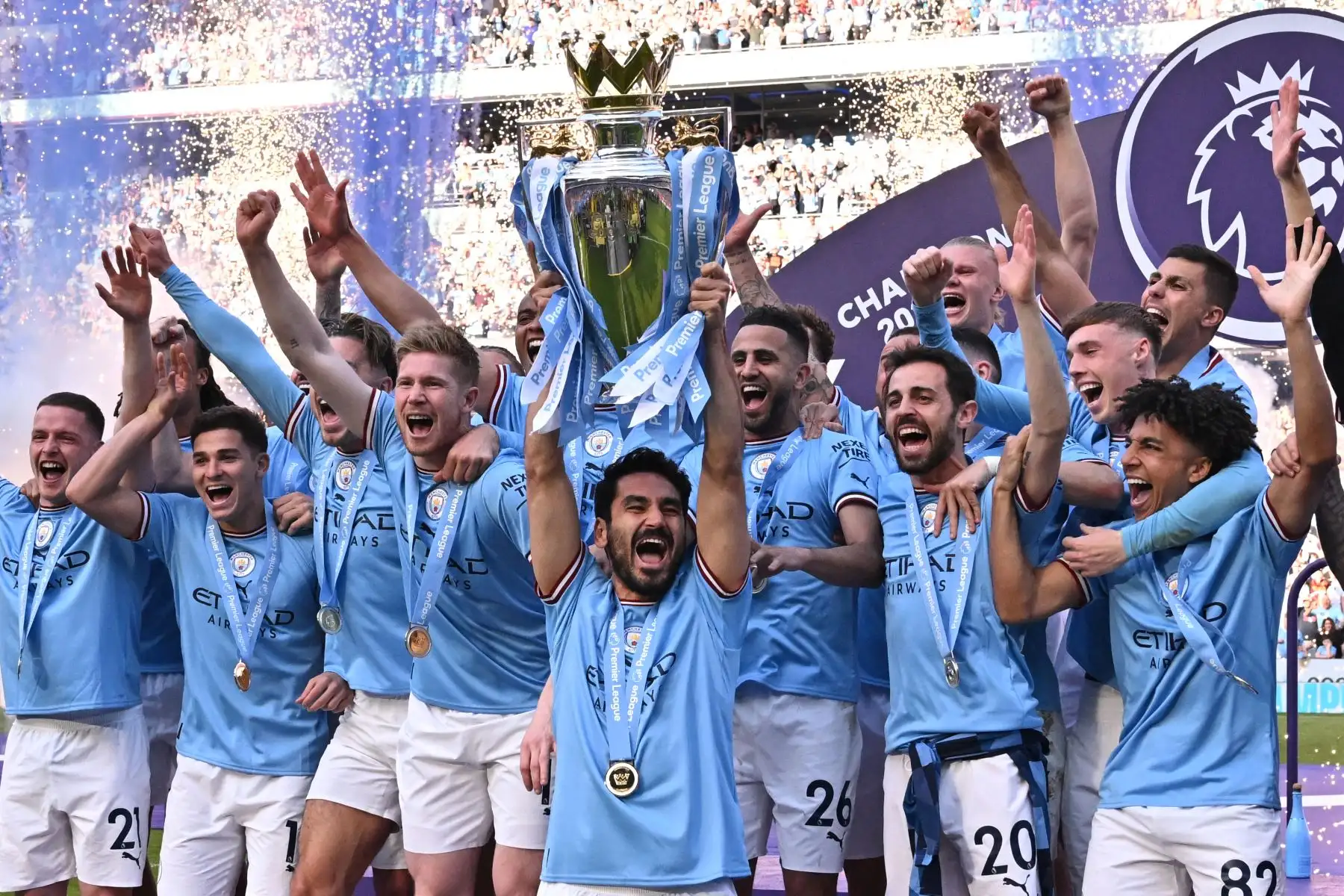 El mediocampista alemán del Manchester City Ilkay Gundogan levanta el trofeo mientras los jugadores del Manchester City celebran ganar el título en la ceremonia de presentación después del partido de fútbol de la Premier League inglesa entre el Manchester City y el Chelsea en el Etihad Stadium en Manchester, noroeste de Inglaterra, el 21 de mayo de 2023. Manchester City ganó la Premier League por quinta vez en seis temporadas el sábado, dando un primer paso hacia un posible triplete dorado de trofeos cuando