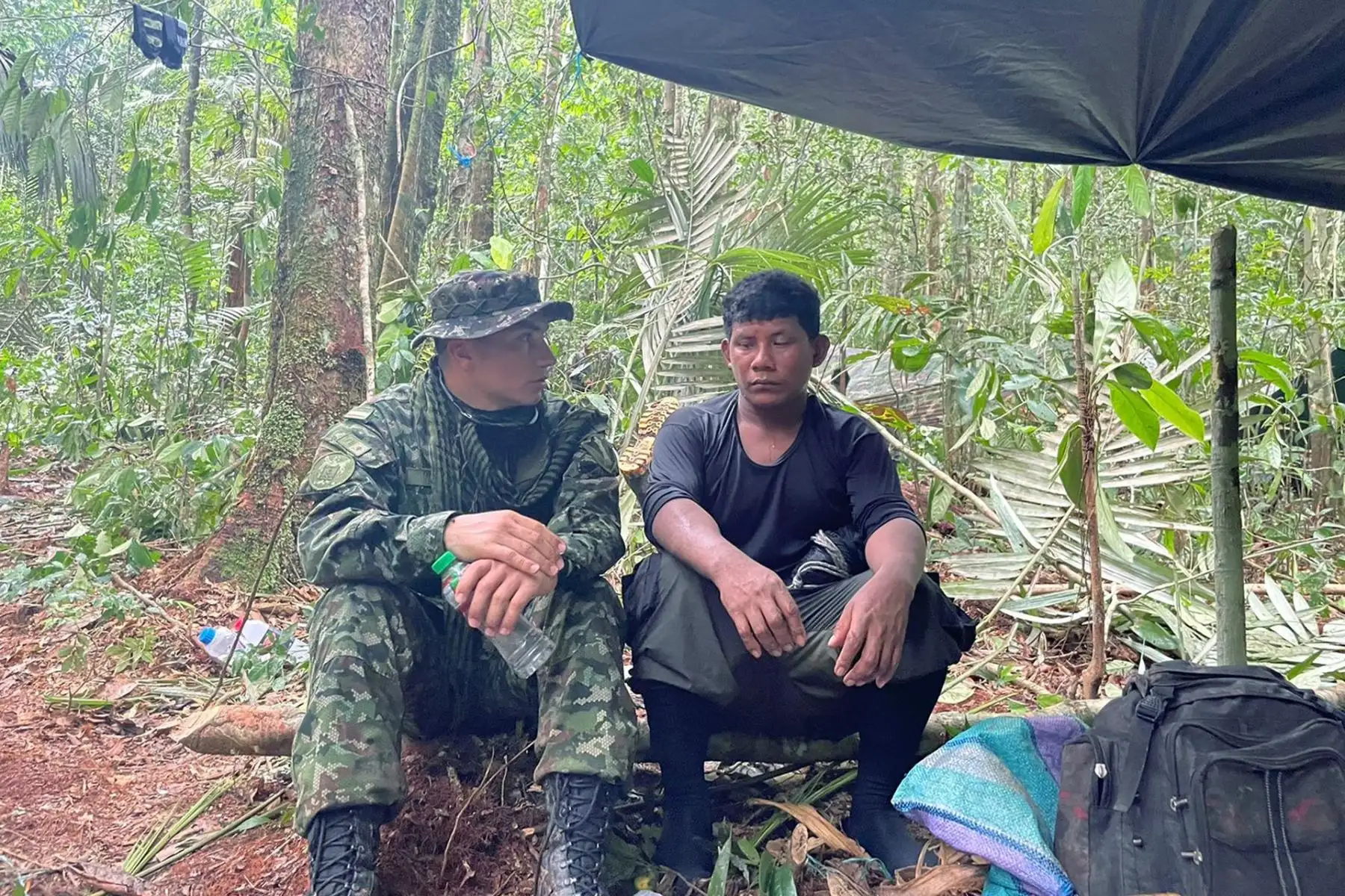 Fotografía cedida hoy por las Fuerzas Militares de Colombia en la que se ve a Manuel Ranoque (d), padre de los cuatro niños desaparecidos en la selva donde ocurrió el siniestro aéreo del Cessna 206, mientras habla con un integrante del Ejército, en medio de la selva donde busca a sus hijos. Foto: EFE
