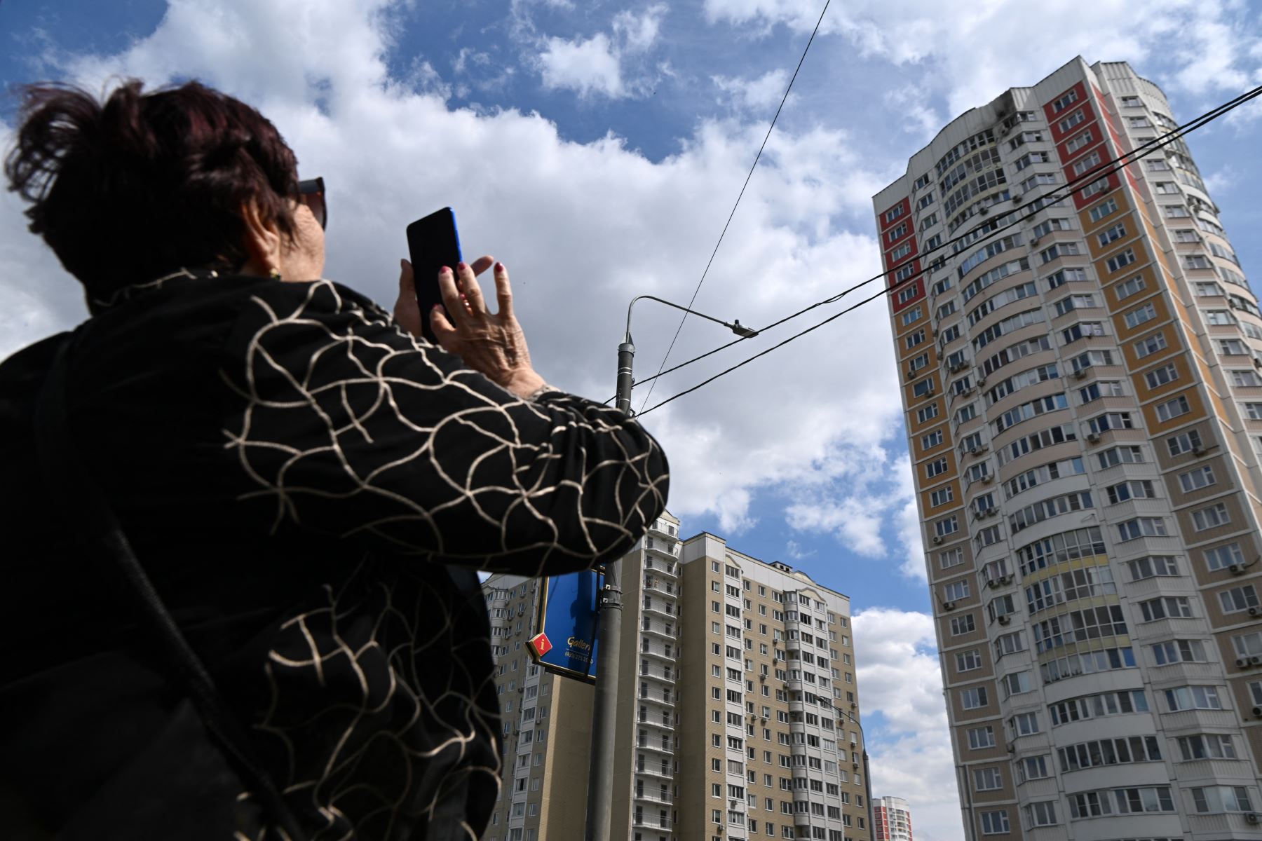 Una mujer toma una fotografía de un edificio de apartamentos de varios pisos dañado después de un ataque con drones en Moscú el 30 de mayo de 2023.
Foto: AFP