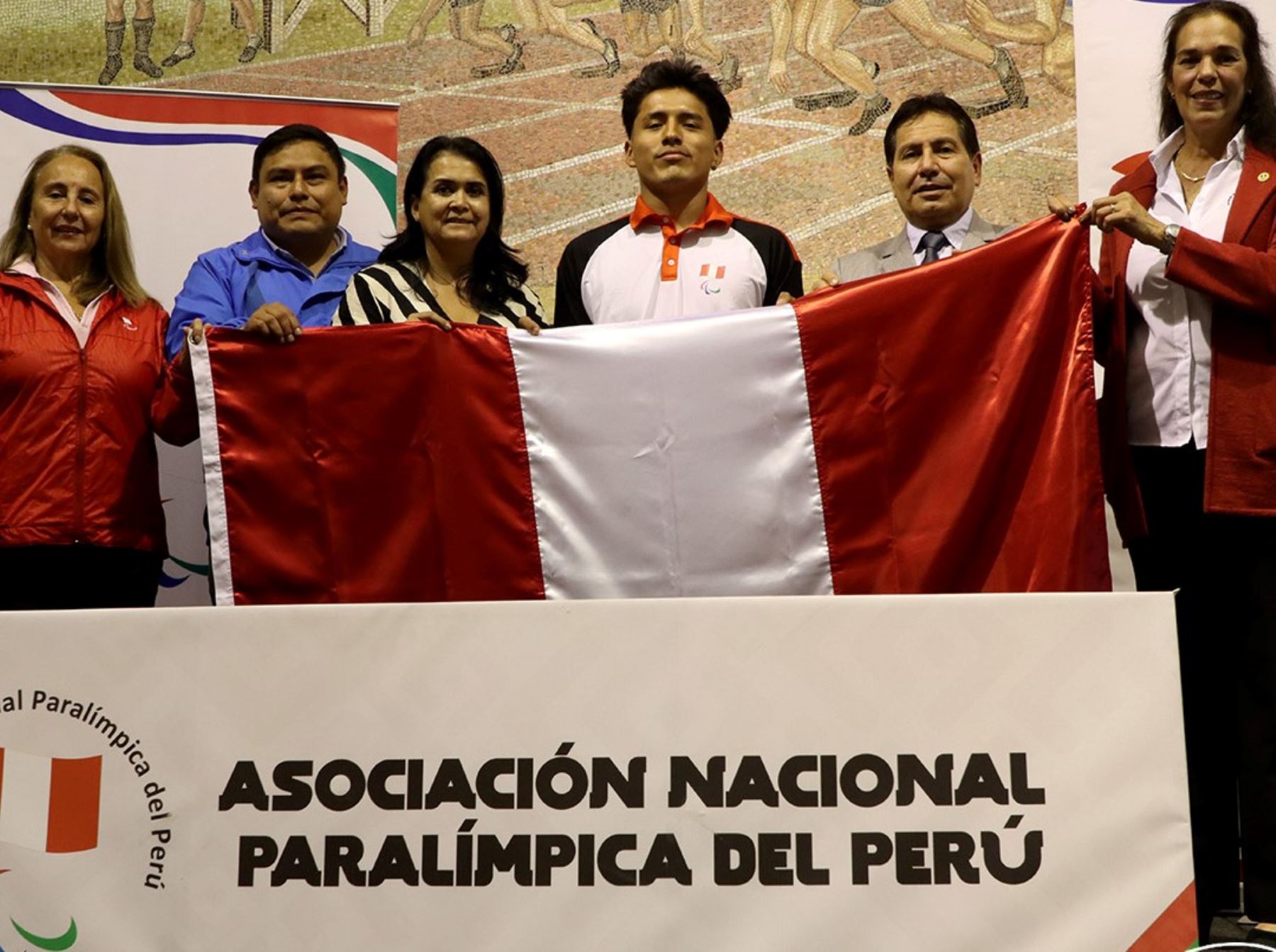 El paraatleta Jesús Castillo recibe la bandera de las manos de la presidente de la Asociación Paralímpica del Perú, Lucha Villar