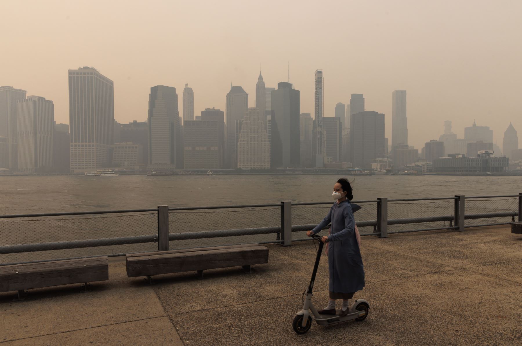 Una persona con una máscara y un scooter pasa mientras los edificios en el bajo Manhattan se ven a través del humo que llena el aire de los incendios forestales en Canadá, en el distrito de Brooklyn de Nueva York, EE. UU.
Foto: EFE