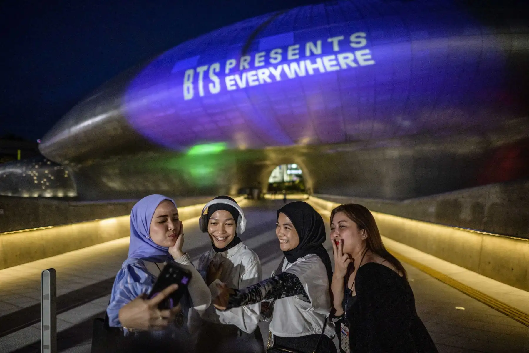 Los fanáticos se toman una selfie frente a Dongdaemun Design Plaza mientras se ilumina con luz púrpura para conmemorar el décimo aniversario de las megaestrellas del K-pop BTS, en Seúl el 12 de junio de 2023.
Foto: AFP Los fanáticos se toman una selfie frente a Dongdaemun Design Plaza mientras se ilumina con luz púrpura para conmemorar el décimo aniversario de las megaestrellas del K-pop BTS, en Seúl el 12 de junio de 2023.
Foto: AFP