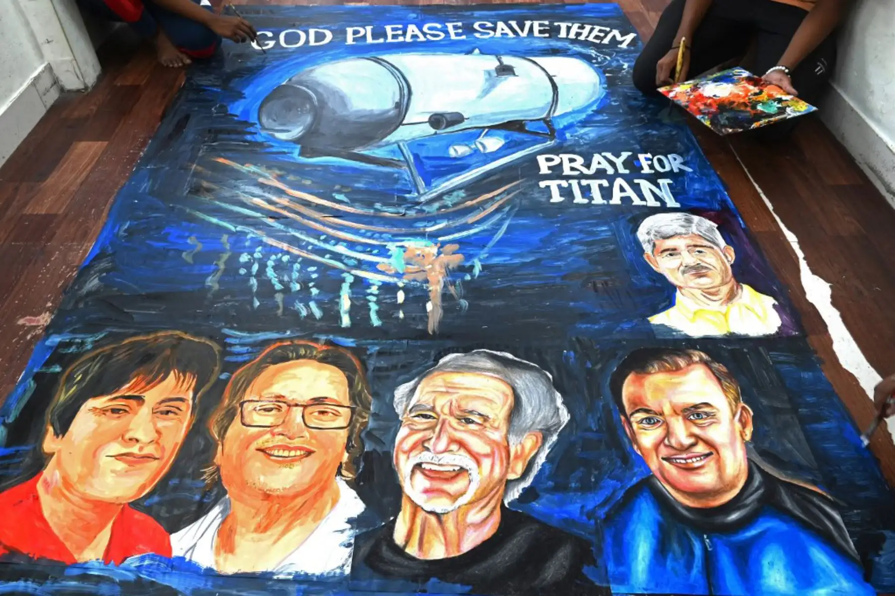 Estudiantes de la escuela de arte dan los toques finales a una pintura que representa a cinco personas a bordo de un sumergible llamado Titán, que desapareció cerca de los restos del Titanic. Foto: AFP