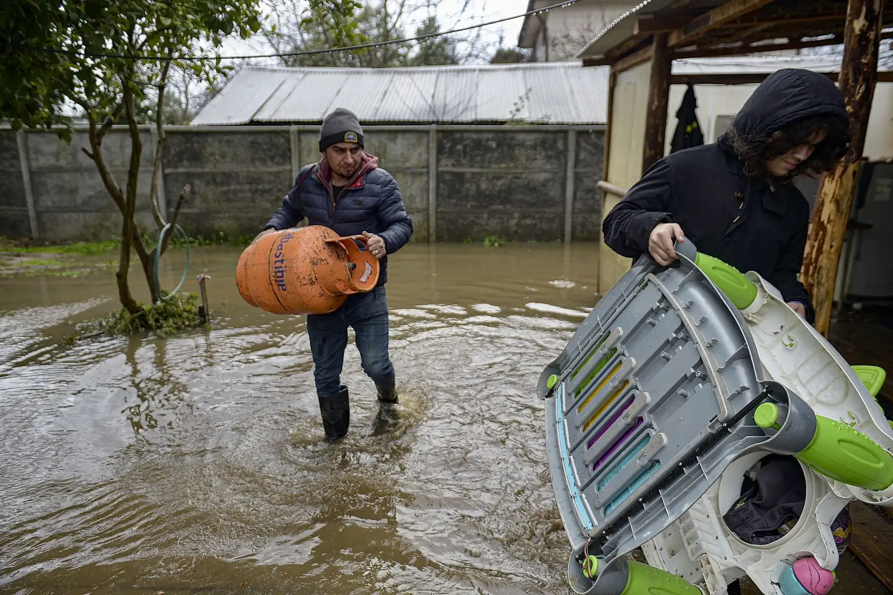 La gente saca sus pertenencias de su casa después de que se inundara por el desbordamiento del río Biobío en Hualqui, a unos 30 km al sur de Concepción, Chile, el 25 de junio de 2023, después de fuertes lluvias en la región. Las lluvias en el centro de Chile han dejado dos muertos, seis desaparecidos, 7.977 aislados y 3.383 sin hogar, informó el 24 de junio la ministra del Interior, Carolina Toha.
Foto: AFP