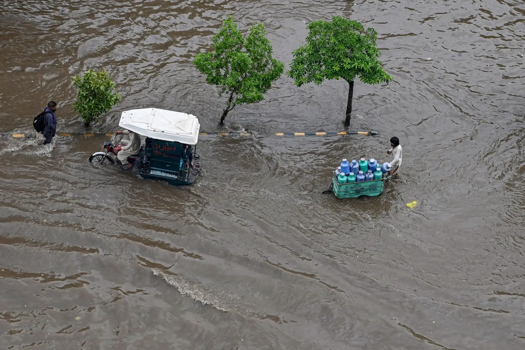 La gente se abre paso a través de un camino inundado después de una fuerte lluvia en Lahore.
Foto: AFP